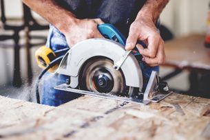 A man is using a circular saw to cut a piece of wood.
