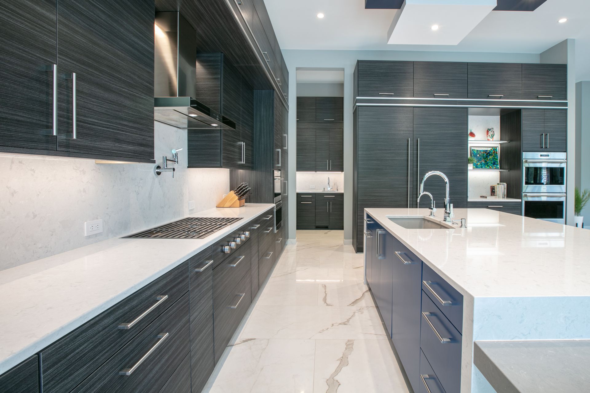 Modern kitchen with dark wood cabinets, white countertops, and a blue island.