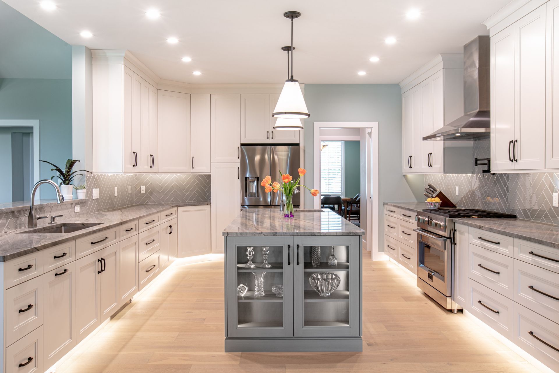 Modern kitchen with white cabinets, stainless steel appliances, and a gray island.