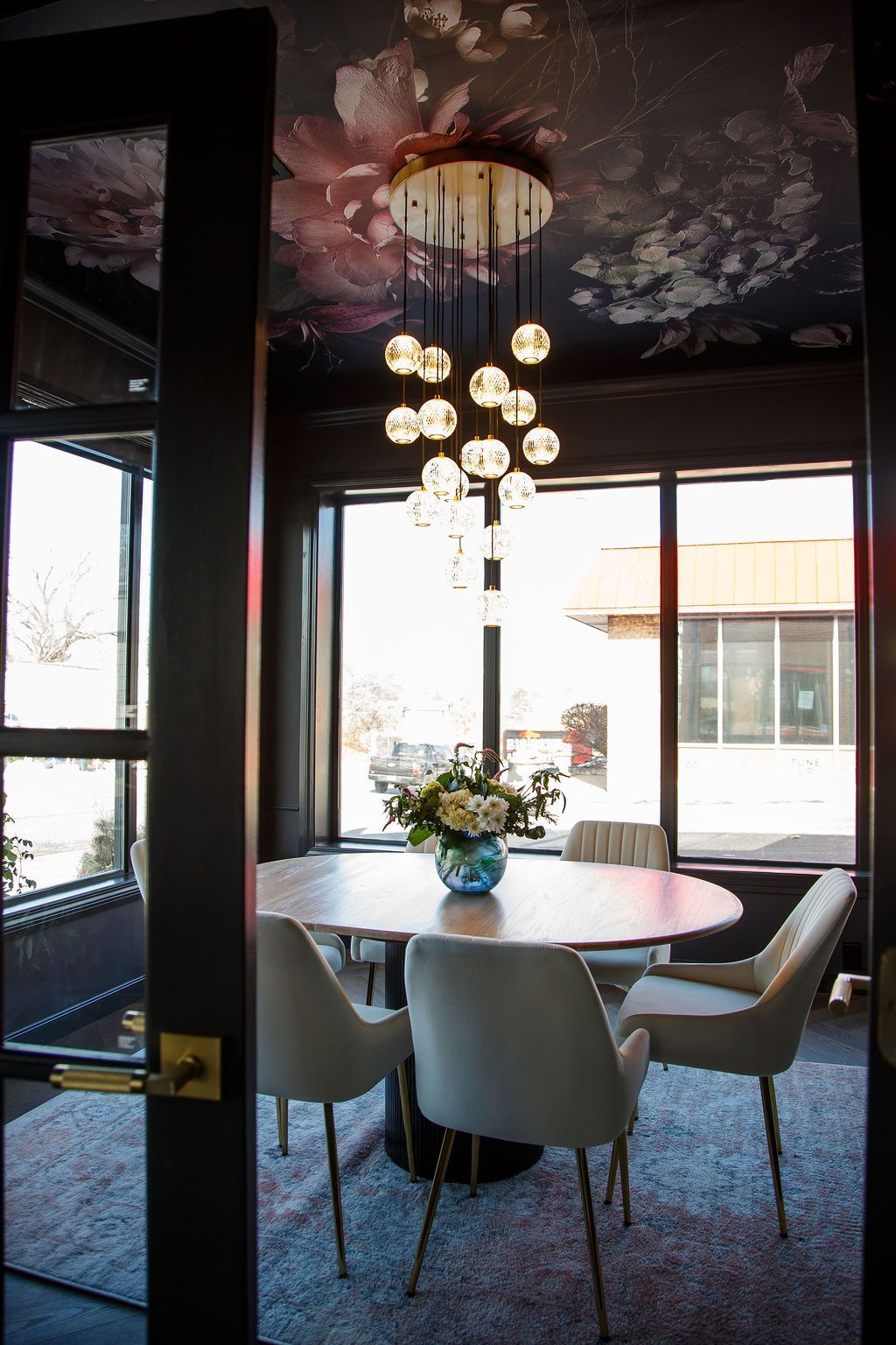 Dining room with round table, chairs, and chandelier; floral ceiling.