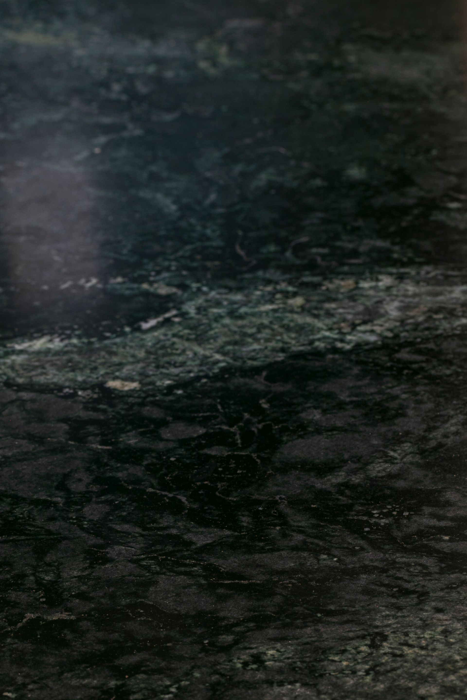 Dark green marble countertop with swirling patterns and streaks of lighter colors.