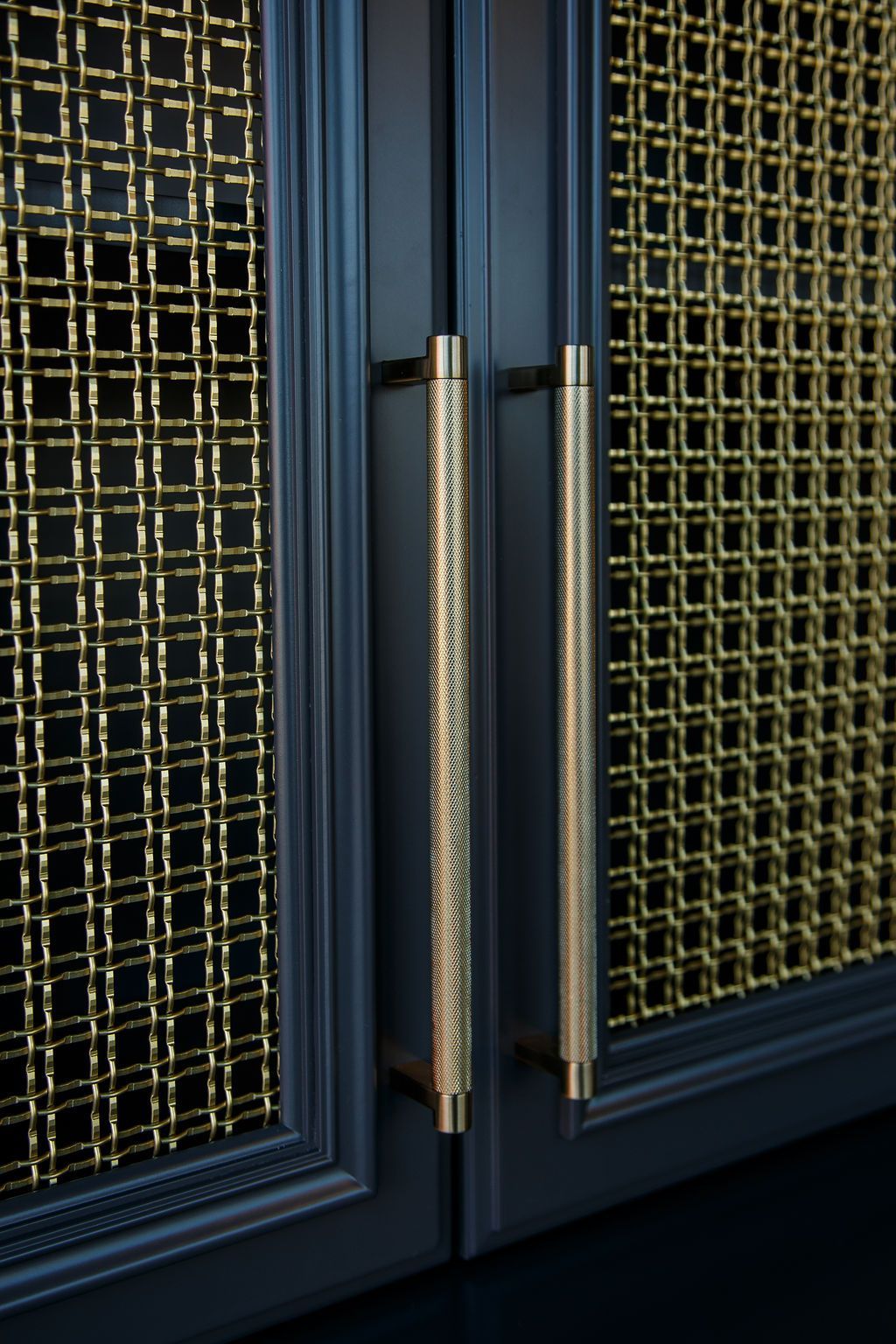 Dark blue cabinet doors with gold mesh panels and textured gold bar handles.