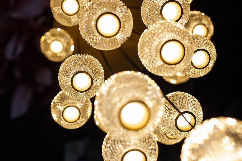 Cluster of illuminated, textured orbs hanging from a ceiling, with warm light emanating from each.