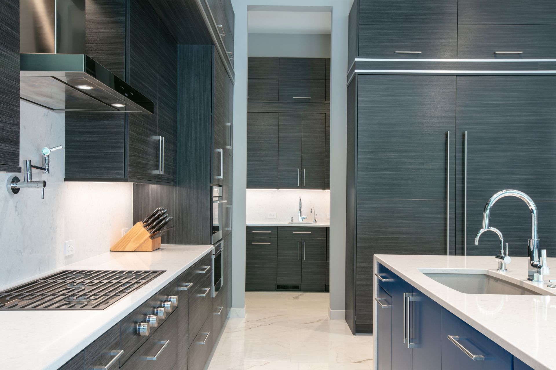 Modern kitchen with dark wood cabinets, stainless steel appliances, and blue island.