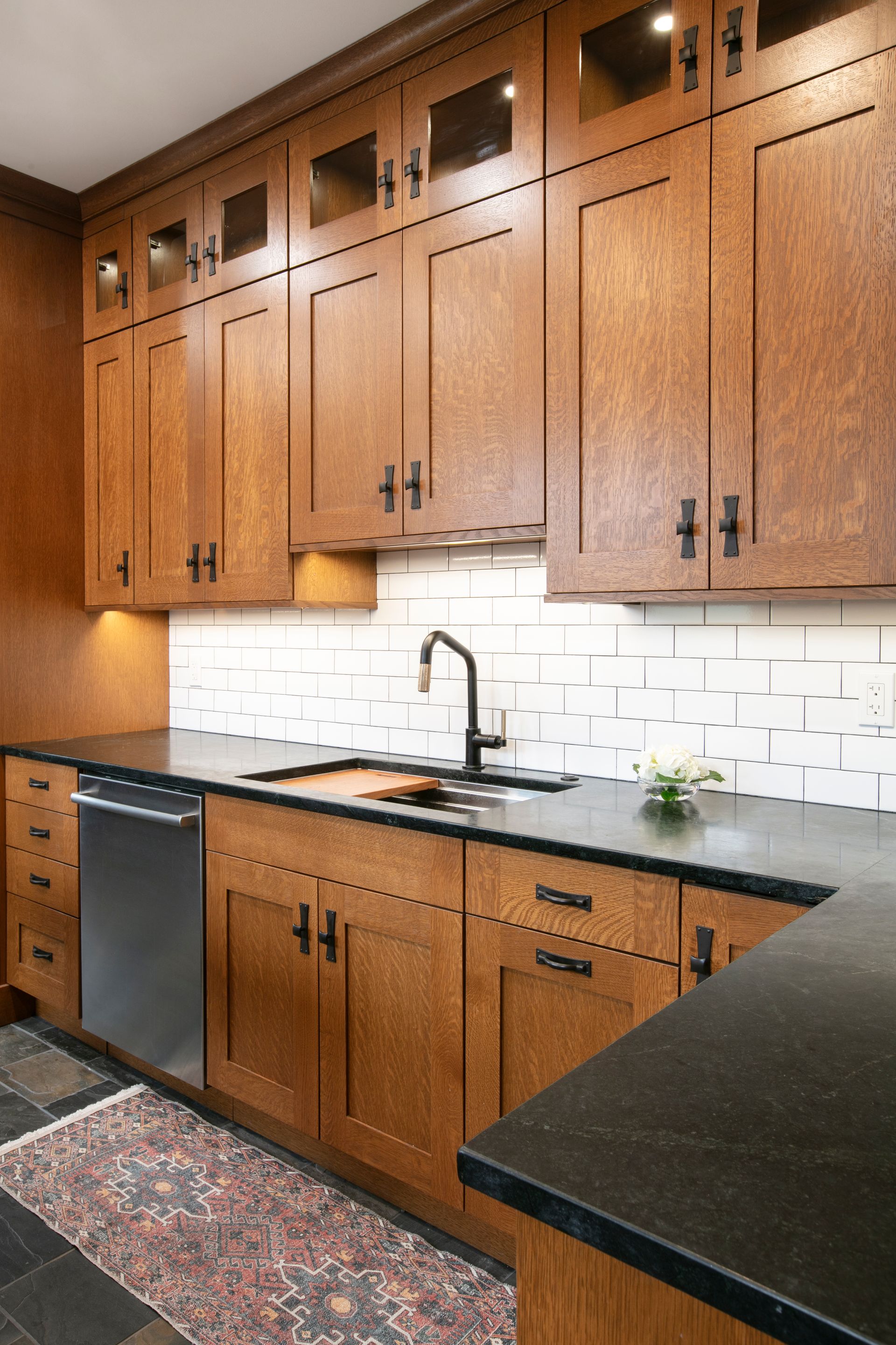 Wooden kitchen cabinets with black countertops and a stainless steel dishwasher.