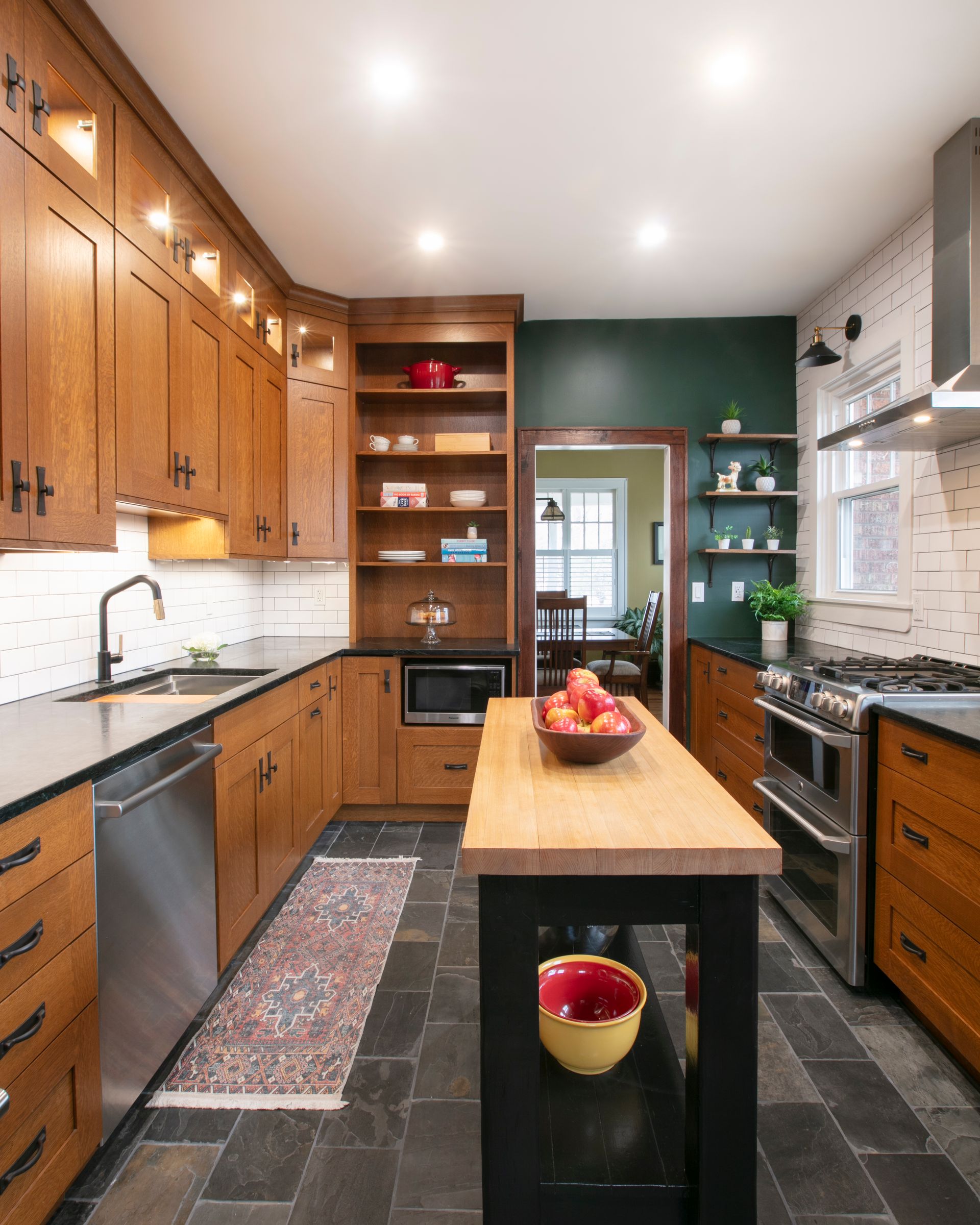 Wooden kitchen with island, dark countertops, and green accent wall.