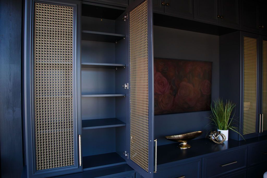 Dark blue cabinet with woven doors, shelves, and artwork.