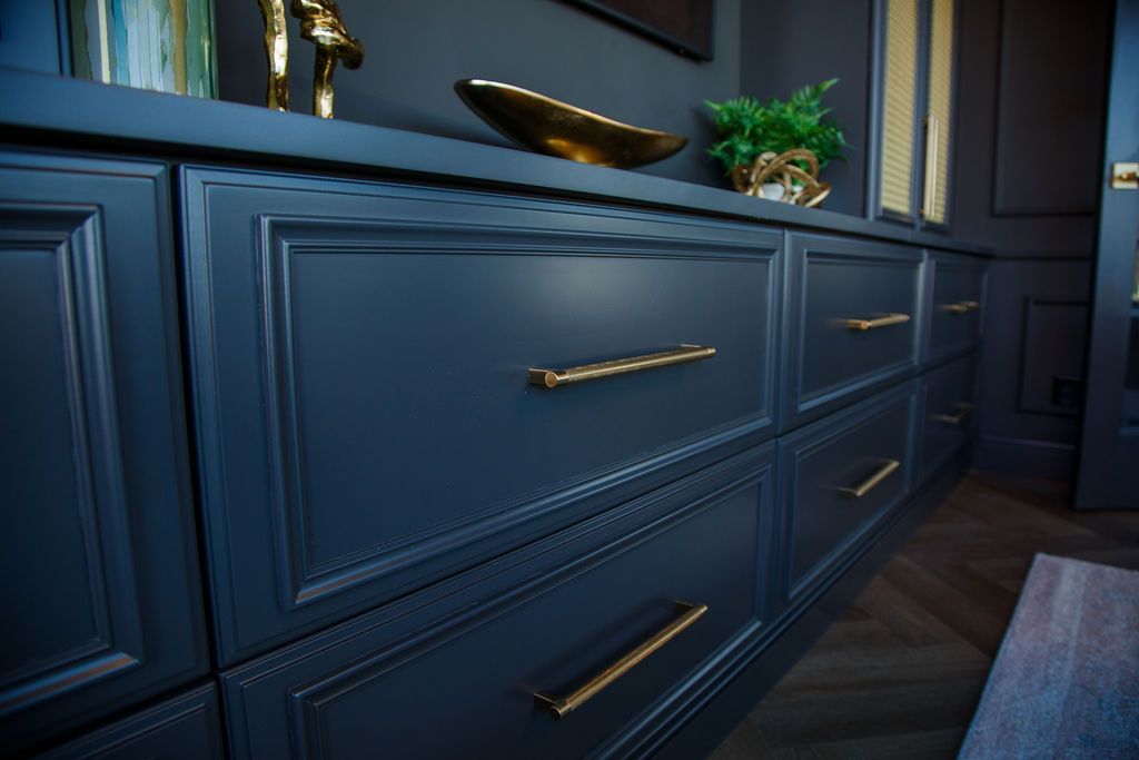 Dark blue cabinets with gold hardware and decorative molding.