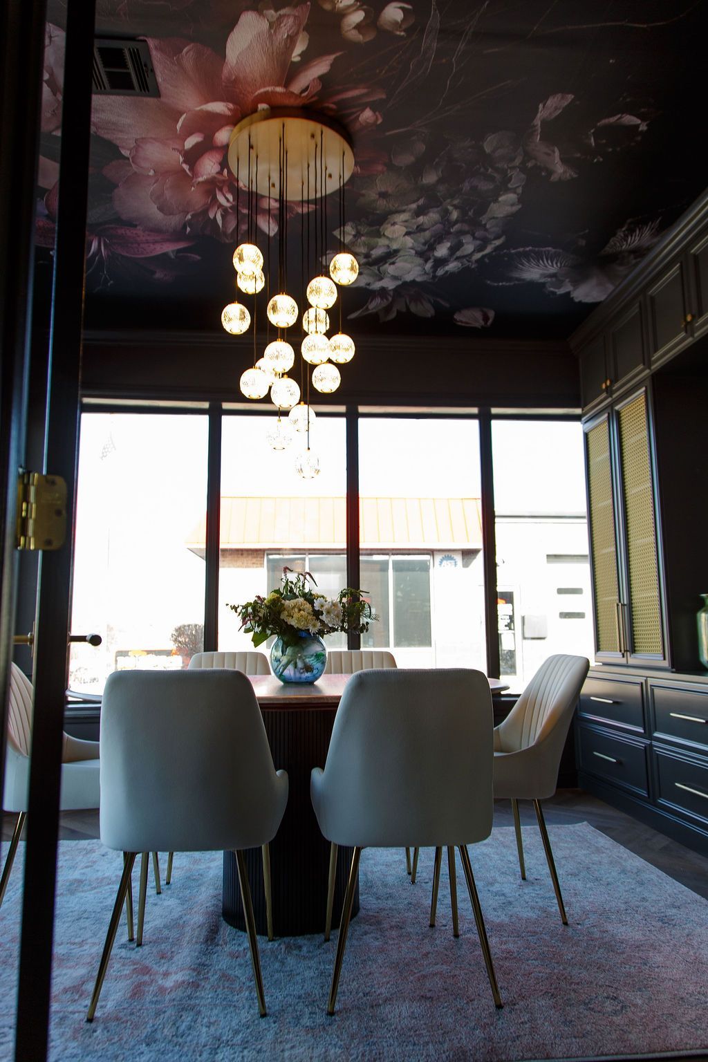 Elegant dining room with floral ceiling, round table, chairs, and chandelier.