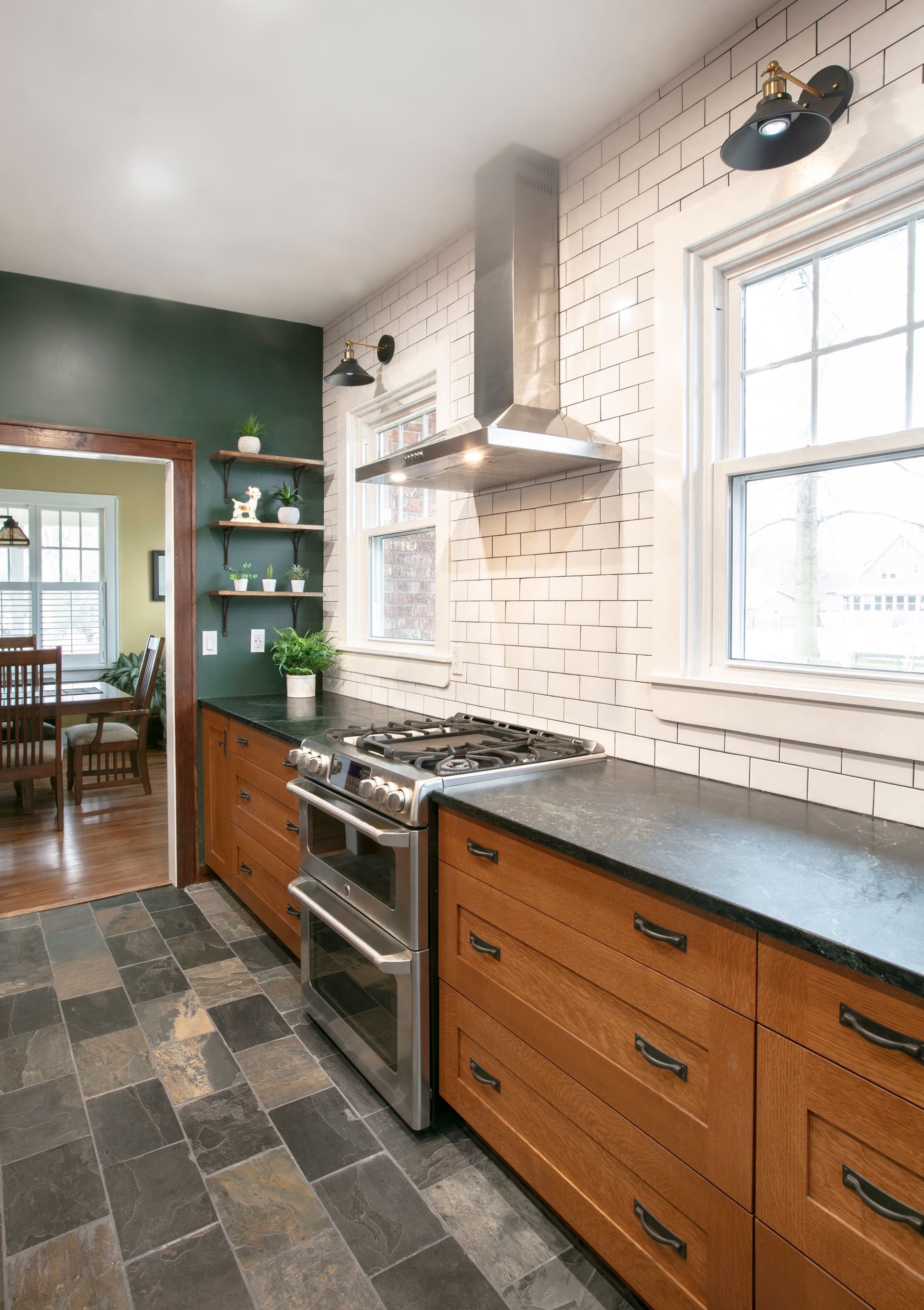Kitchen with wood cabinets, stainless steel appliances, dark countertops, and a brick-patterned backsplash.