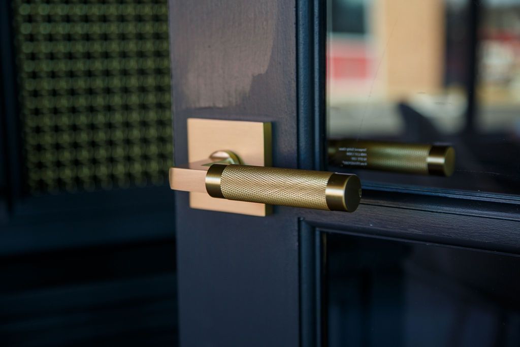 Brass door handle with textured grip on dark door frame.