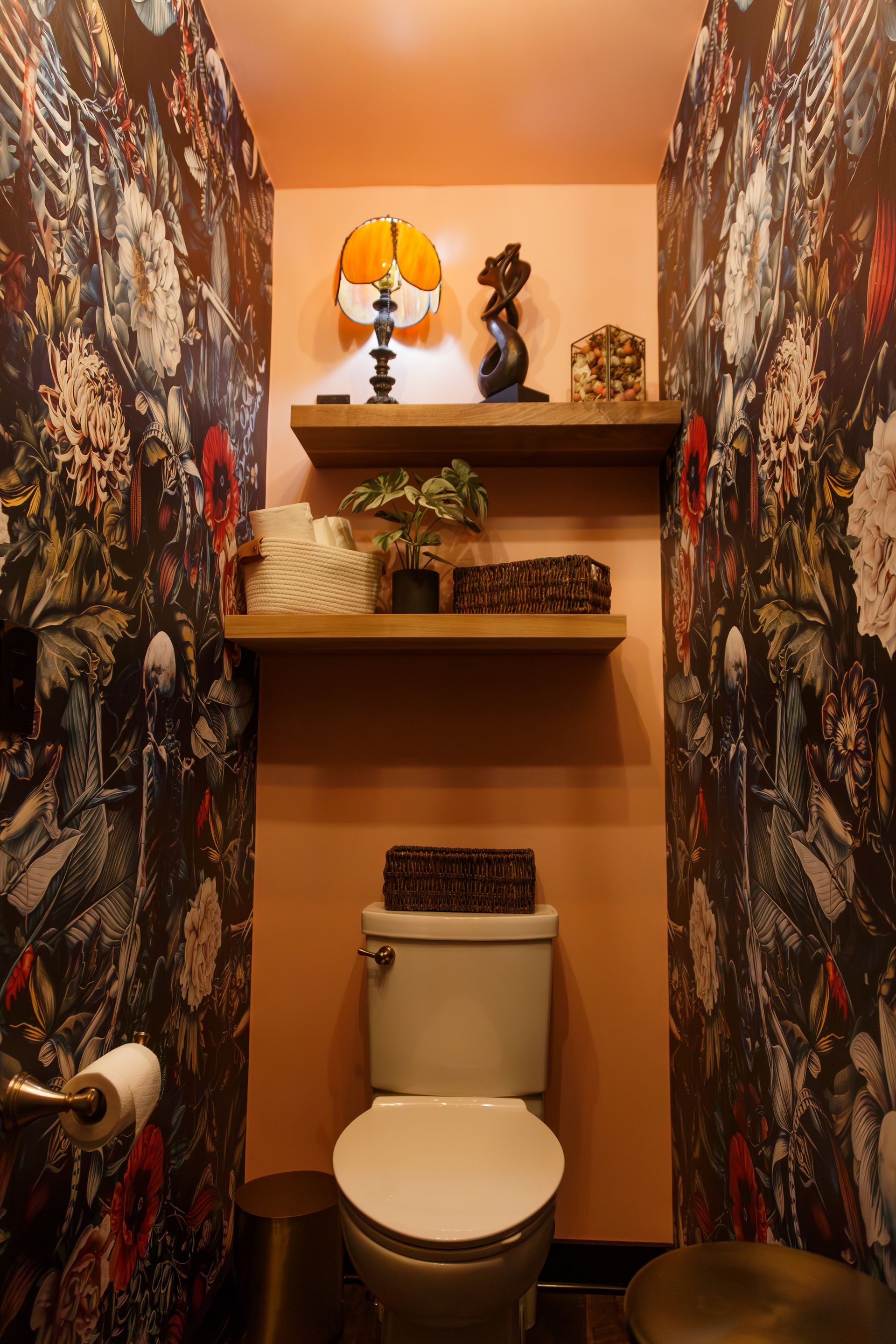 Small powder room with floral wallpaper, floating shelves, and a toilet.