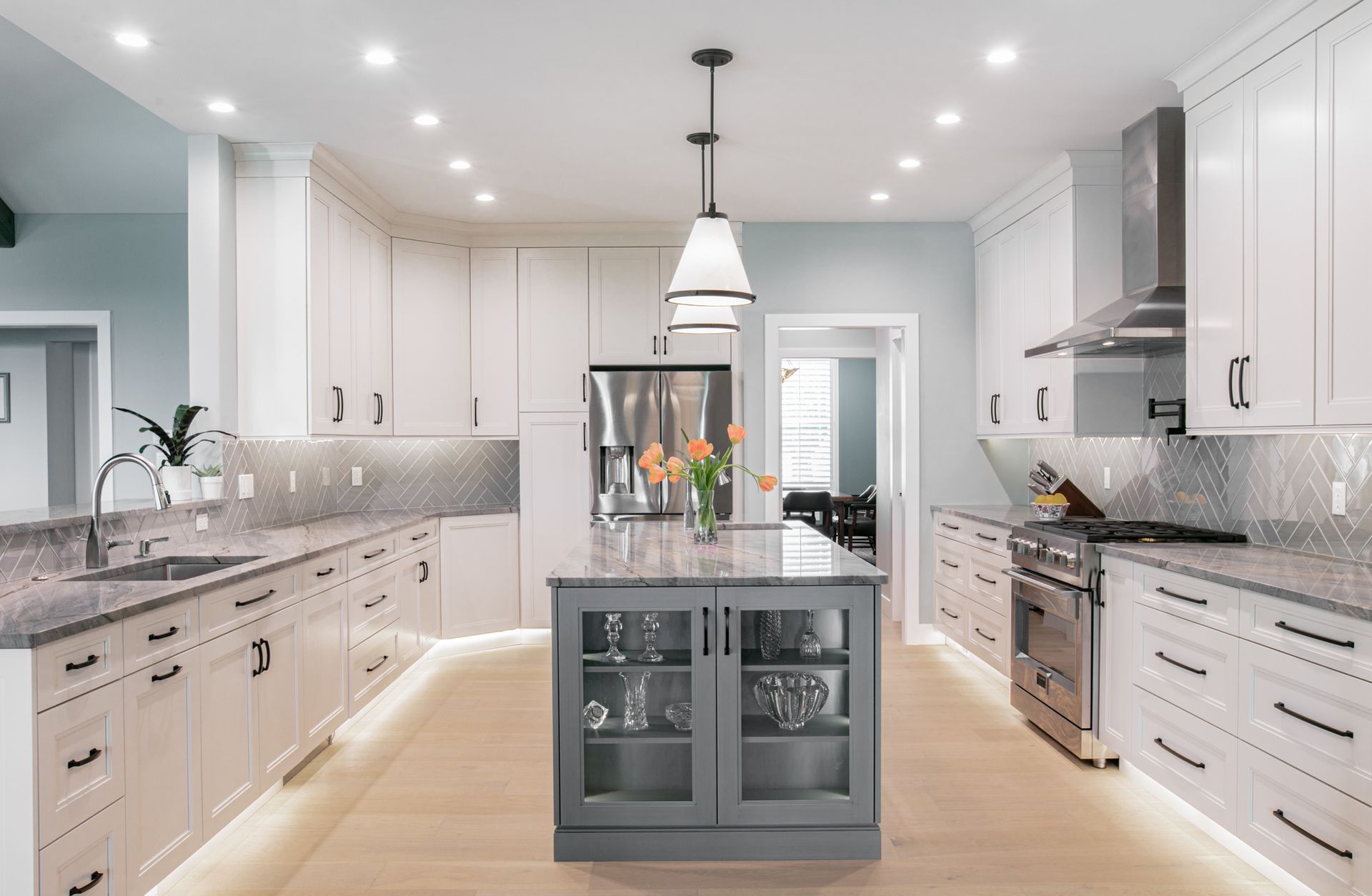 Modern kitchen with white cabinets, gray countertops, and a gray island.