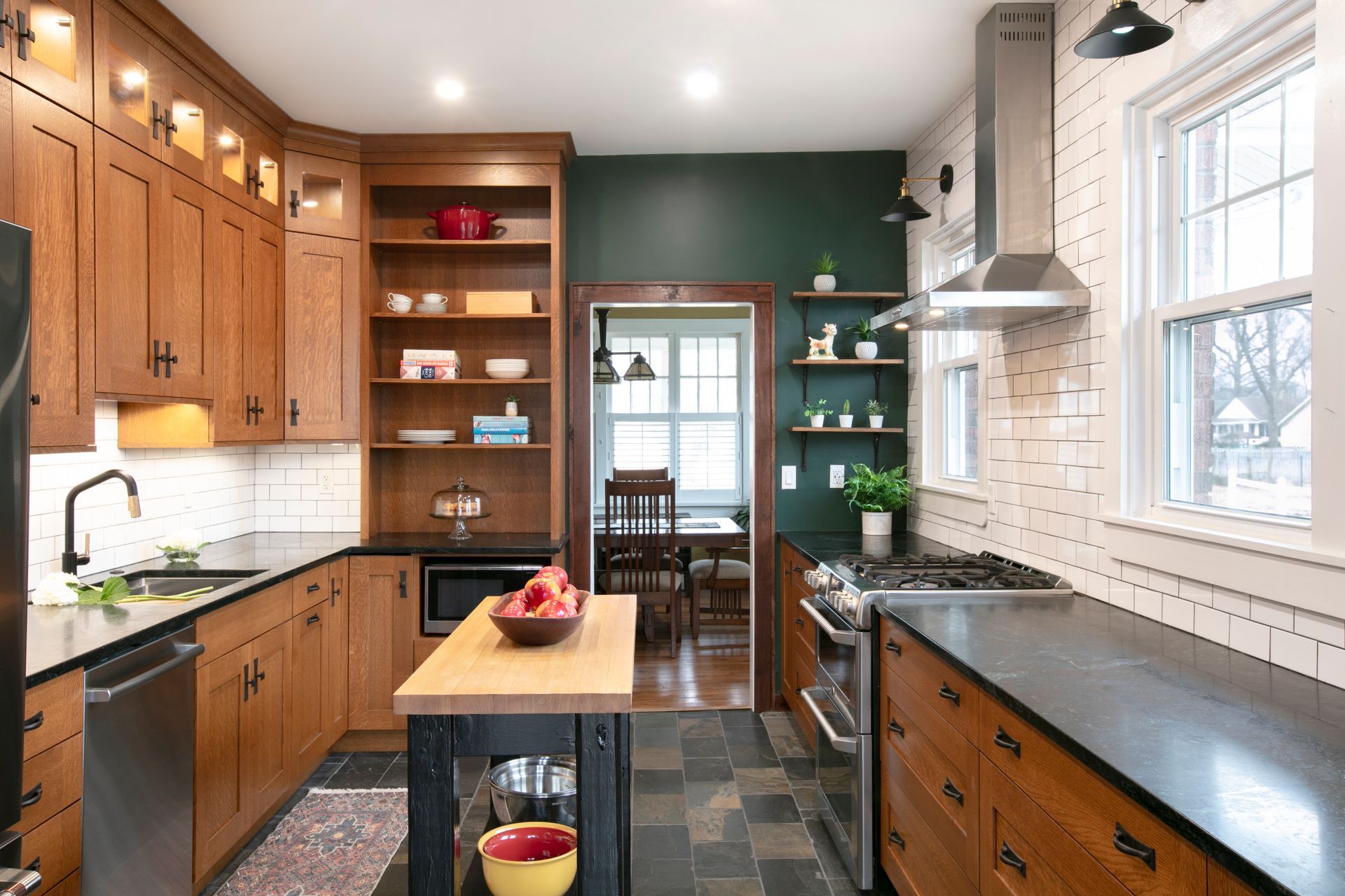 Kitchen with wooden cabinets, black countertops, and a small island. Dark green accent wall.