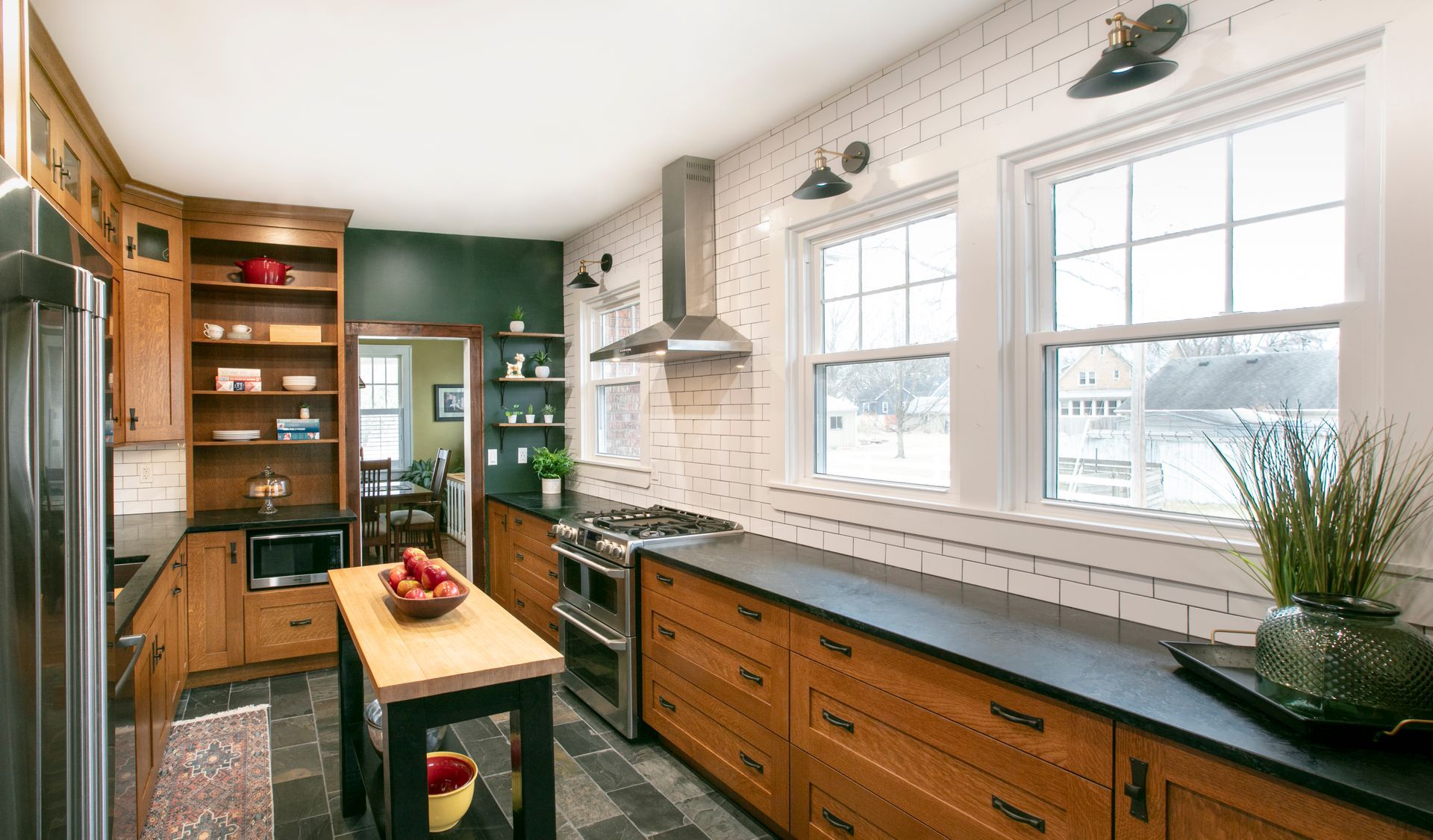 Kitchen with wood cabinets, black countertops, stainless steel appliances, and two windows.