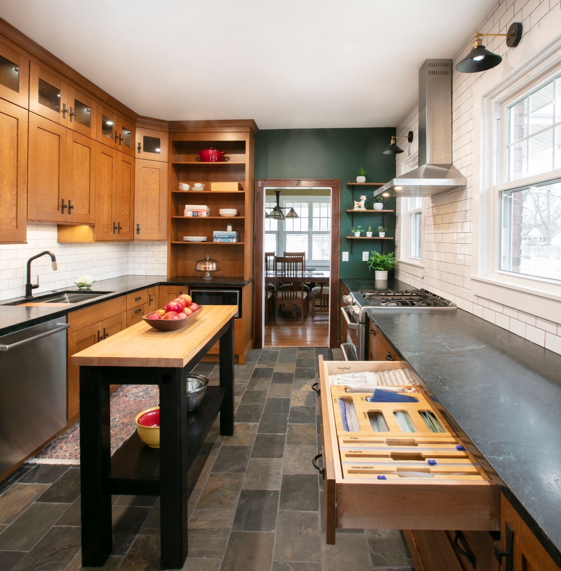 Kitchen with wood cabinets, dark countertops, a black island, and dark tiled floor.