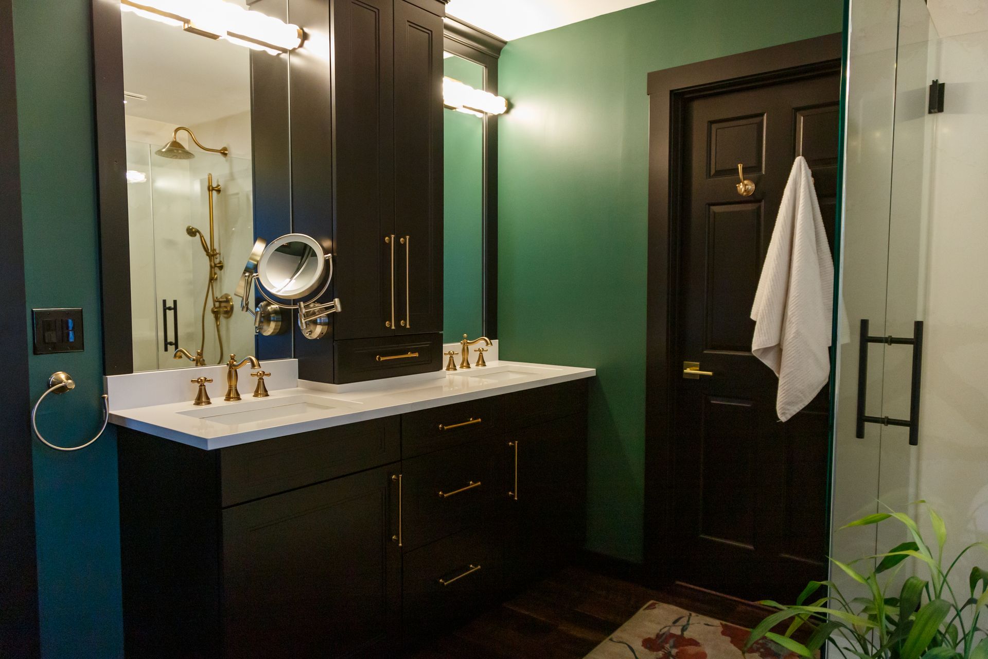 Bathroom with black vanity, gold fixtures, green walls, and white countertop.