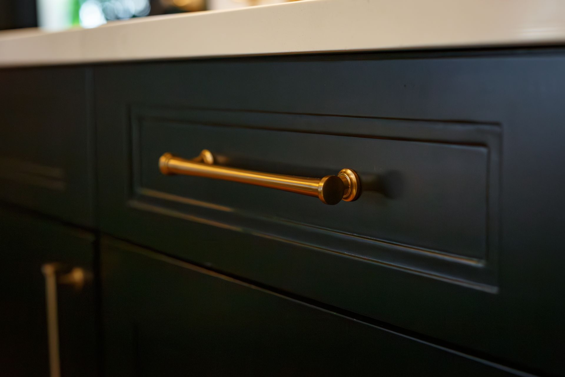 Close-up of a dark green kitchen cabinet with a gold handle.