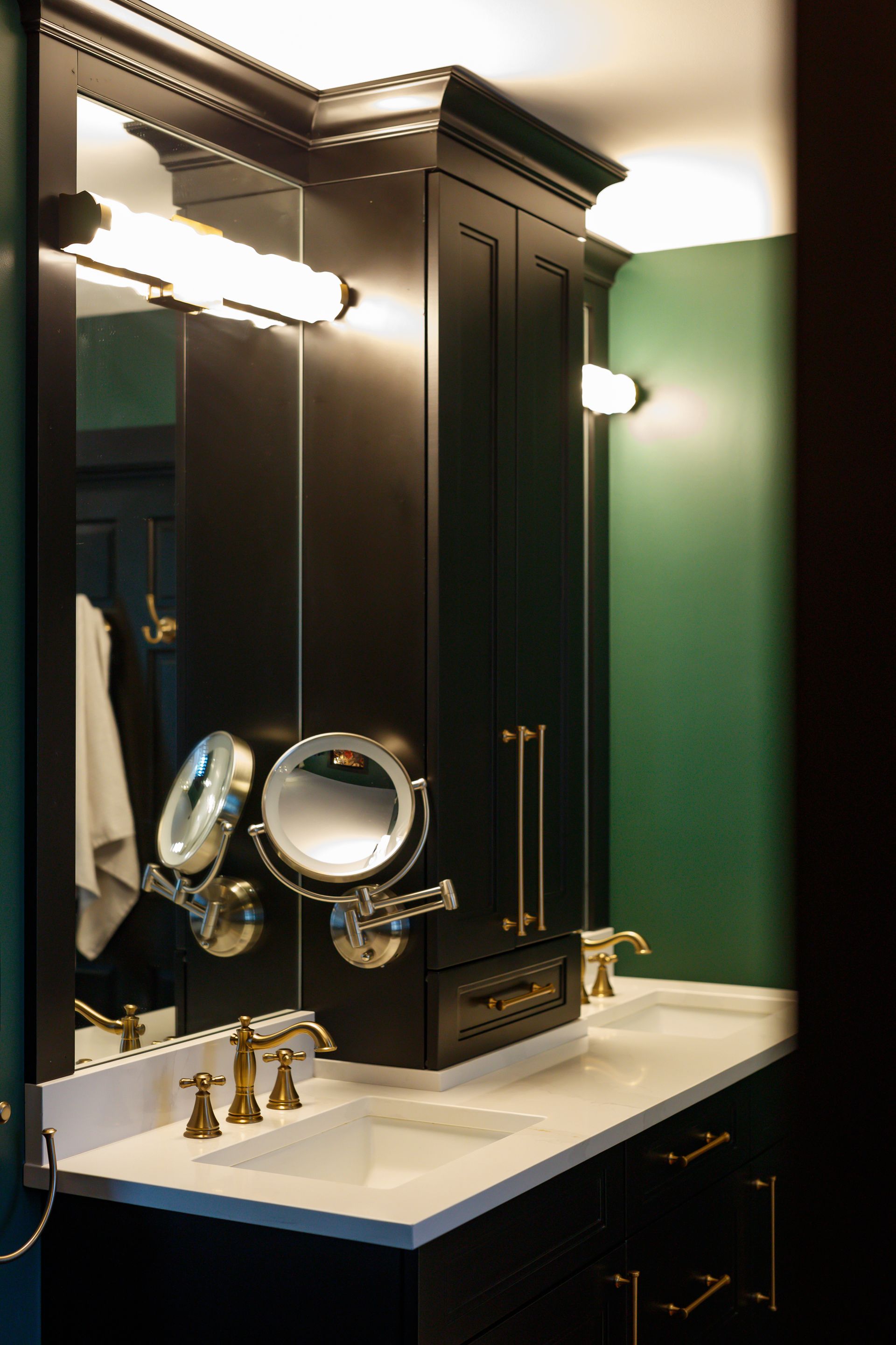 Black bathroom vanity with gold fixtures, white countertop, and green wall.