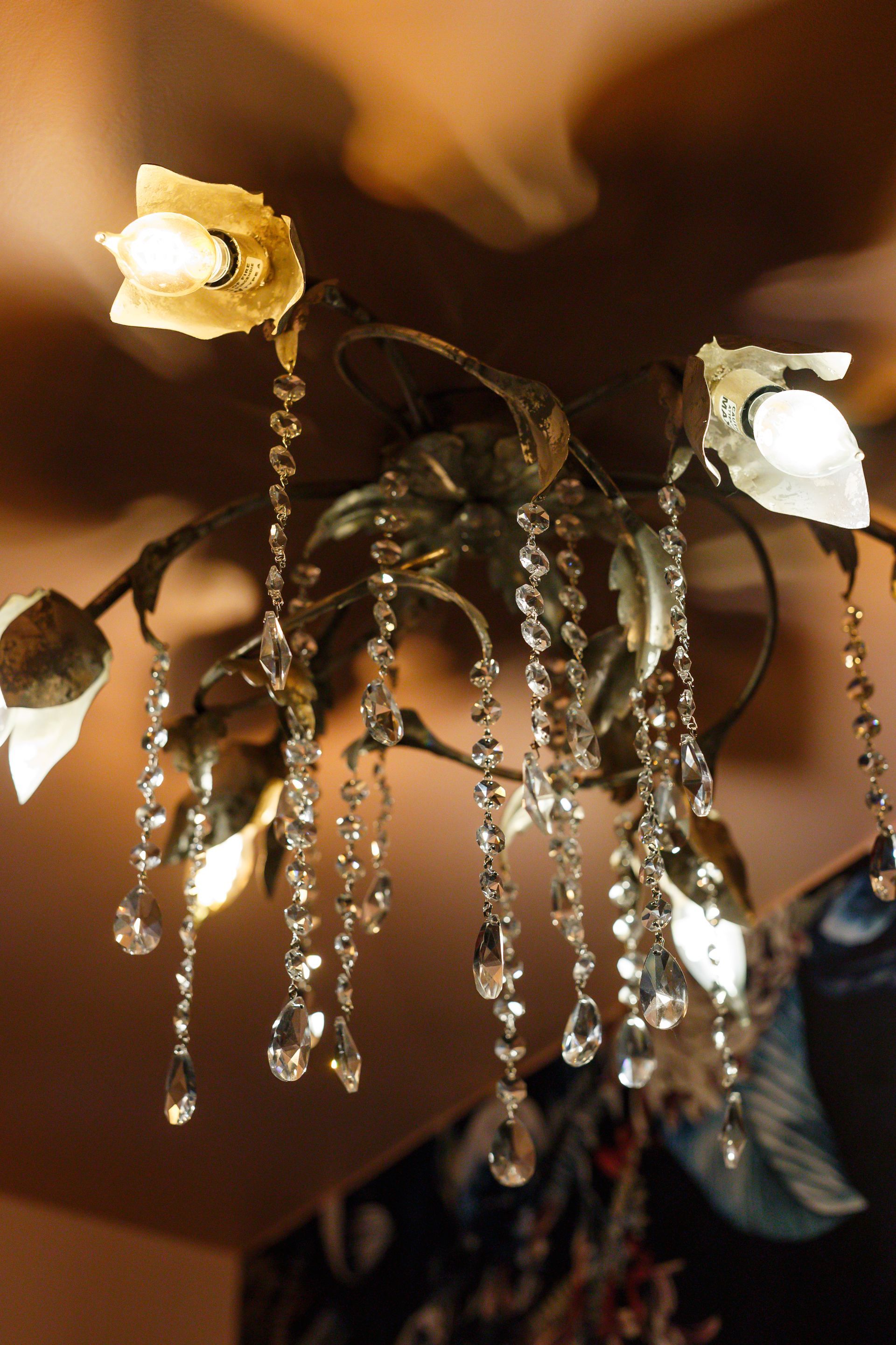 Ornate chandelier with crystal strands and tulip-shaped lights against a warm-toned ceiling.