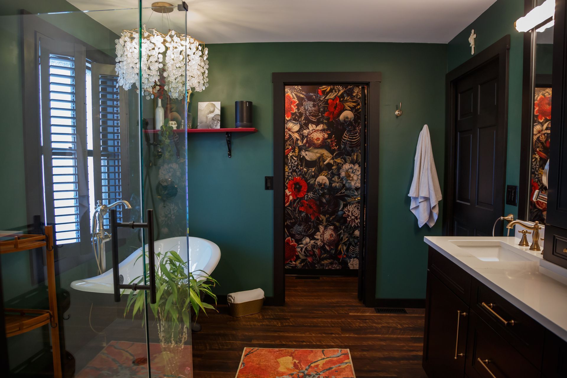 Elegant bathroom with dark green walls, floral wallpaper door, and a clawfoot tub.