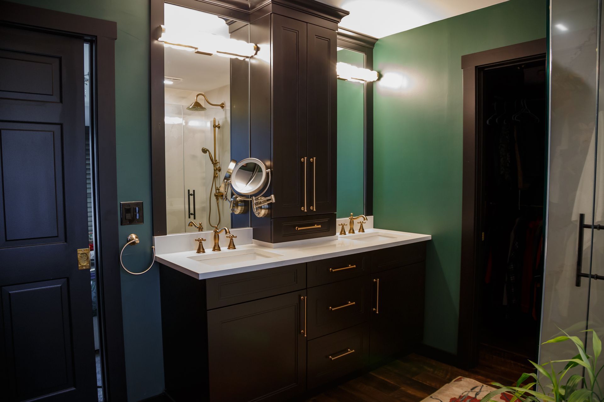 Dark green bathroom with black vanity, white countertop, and gold fixtures.
