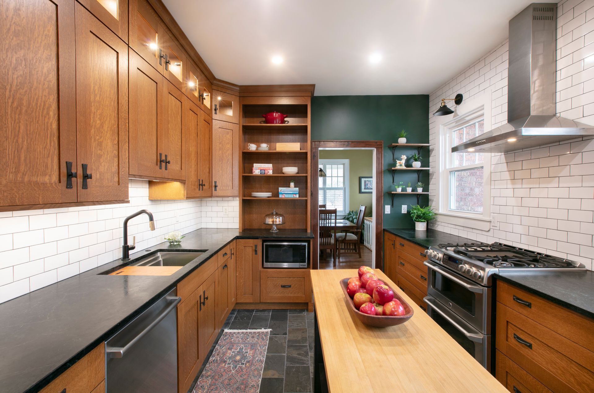 Kitchen renovation with wooden cabinets, black countertops, and a butcher block island.