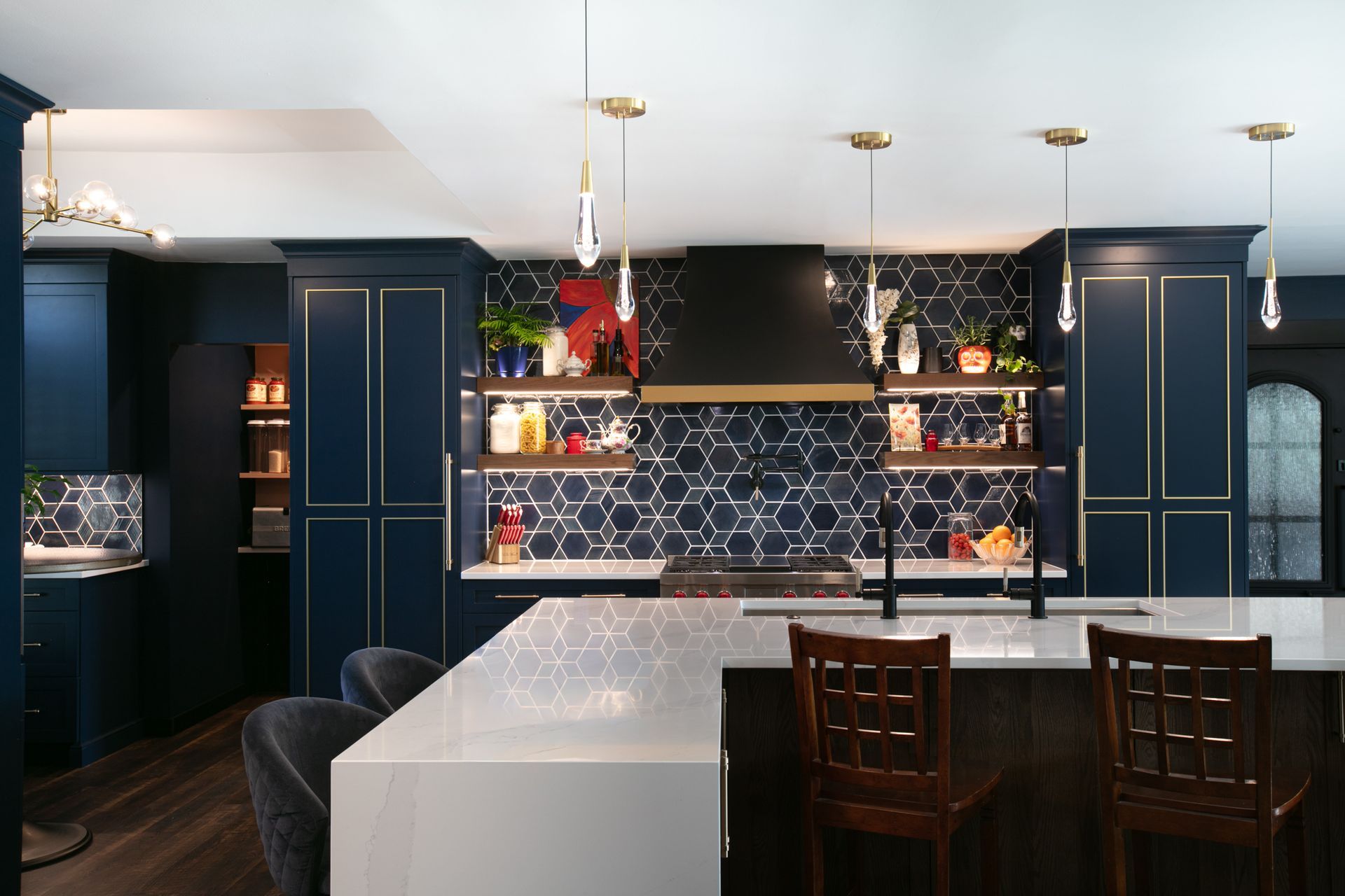 Modern kitchen with navy blue cabinets, white countertops, and gold accents.