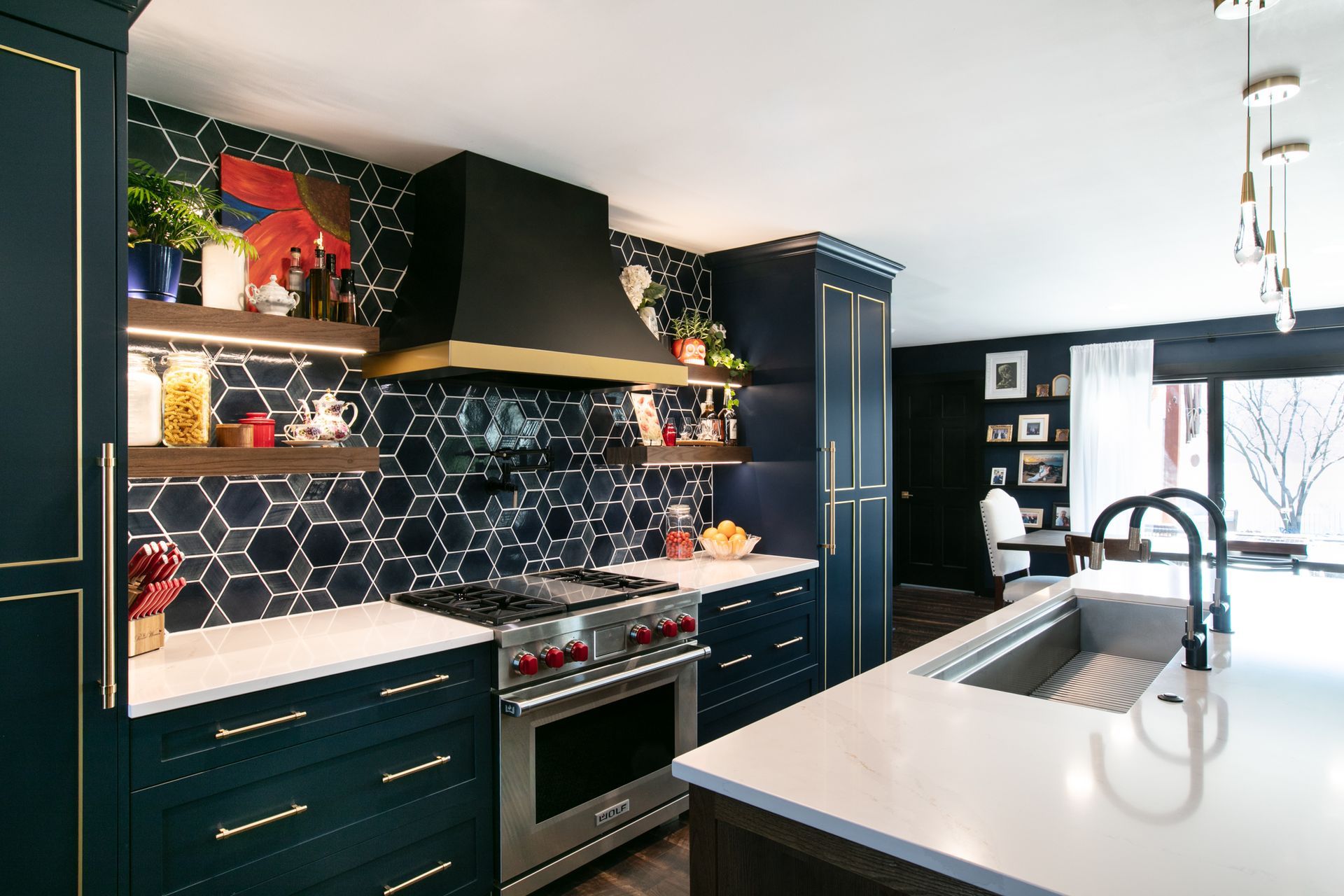 Dark blue kitchen with white countertops, stainless steel appliances, and hexagon tile backsplash.