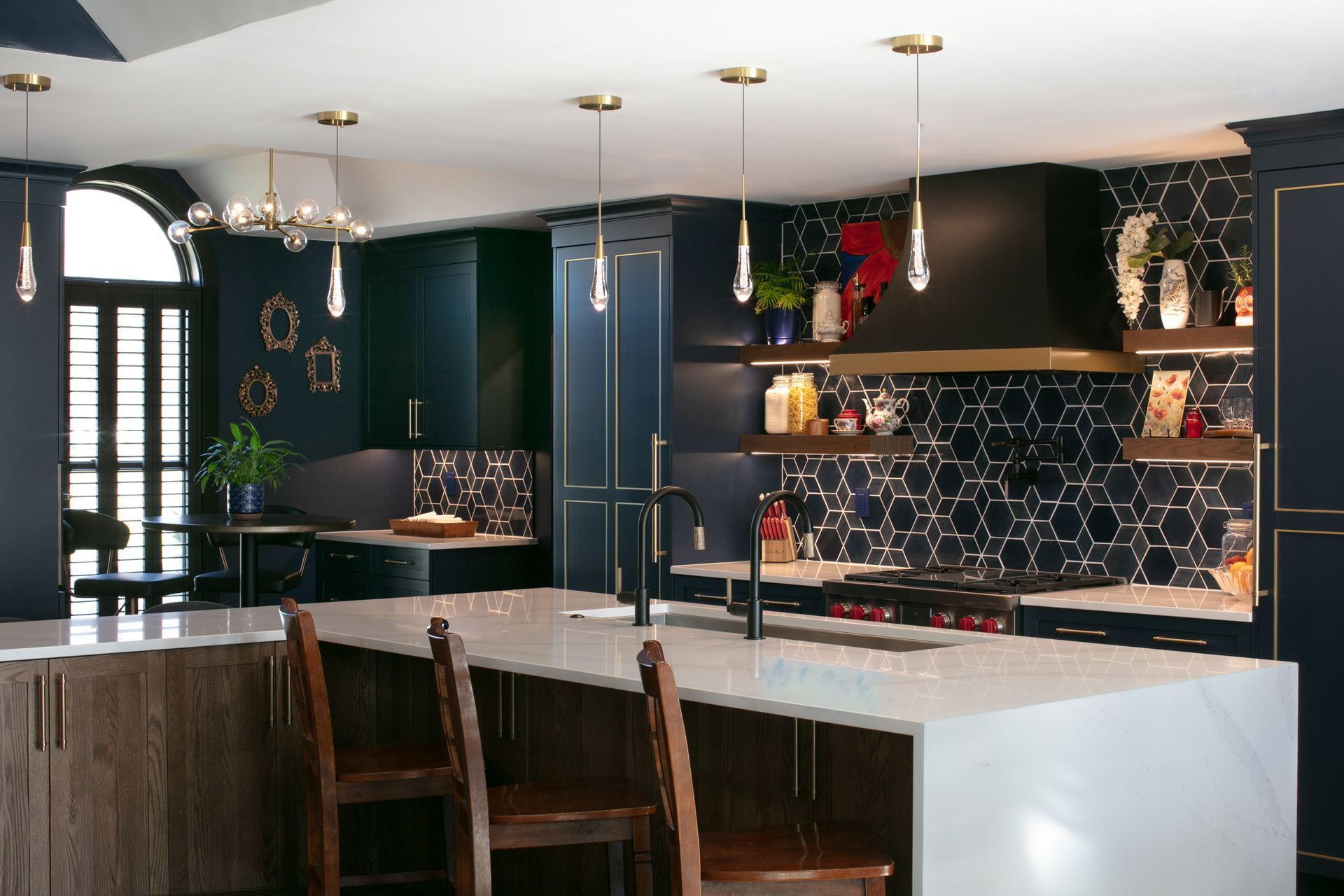 Modern kitchen with dark blue cabinetry, gold accents, white countertops, and a large island.