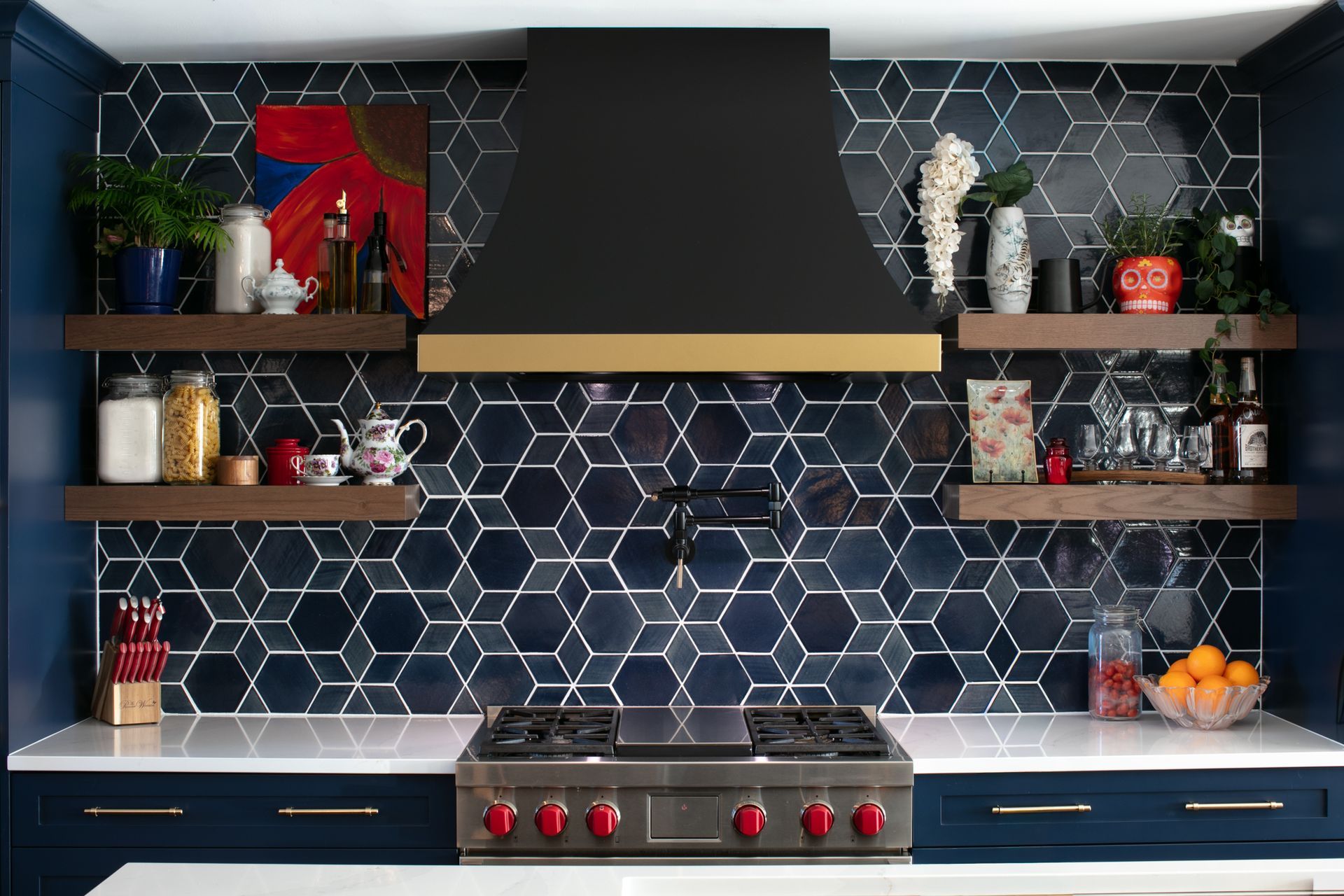 Kitchen with blue hexagon tile backsplash, black range hood, open shelves, and navy cabinets.