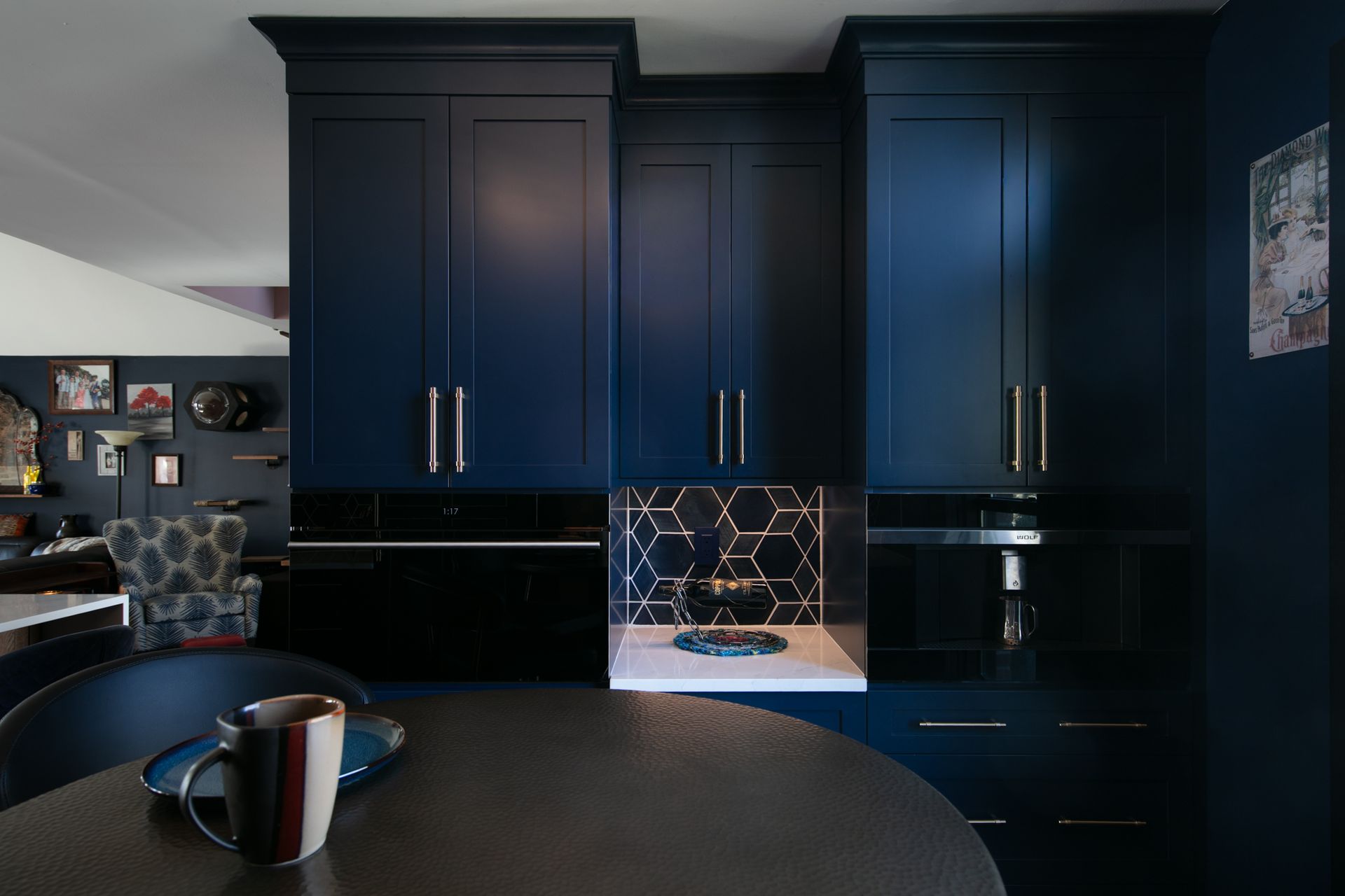 Dark blue kitchen cabinets with a black countertop and a round table with a mug.