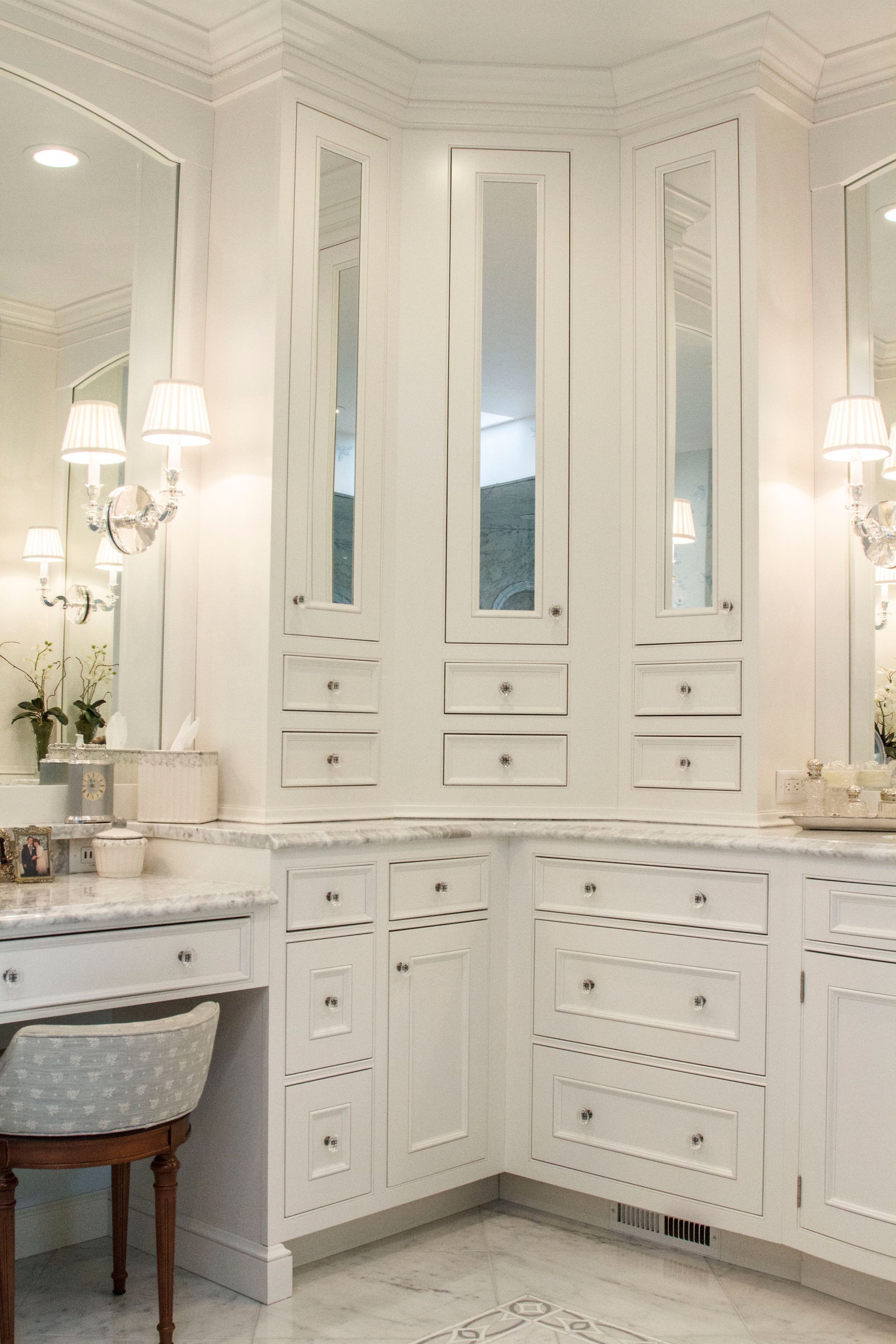White bathroom with mirrors, cabinets, and a vanity corner.