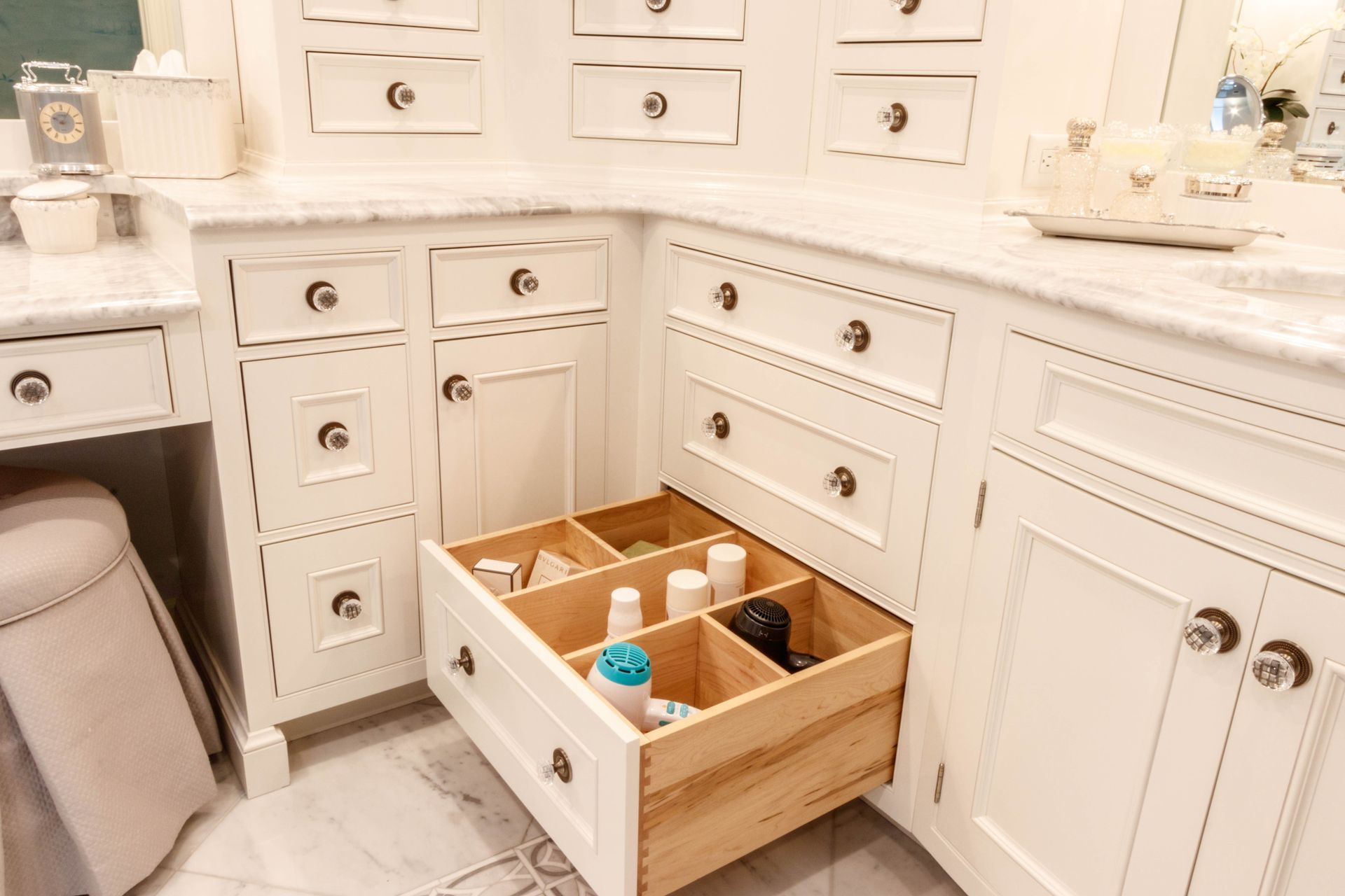 White bathroom vanity with drawers; one open with organizers.