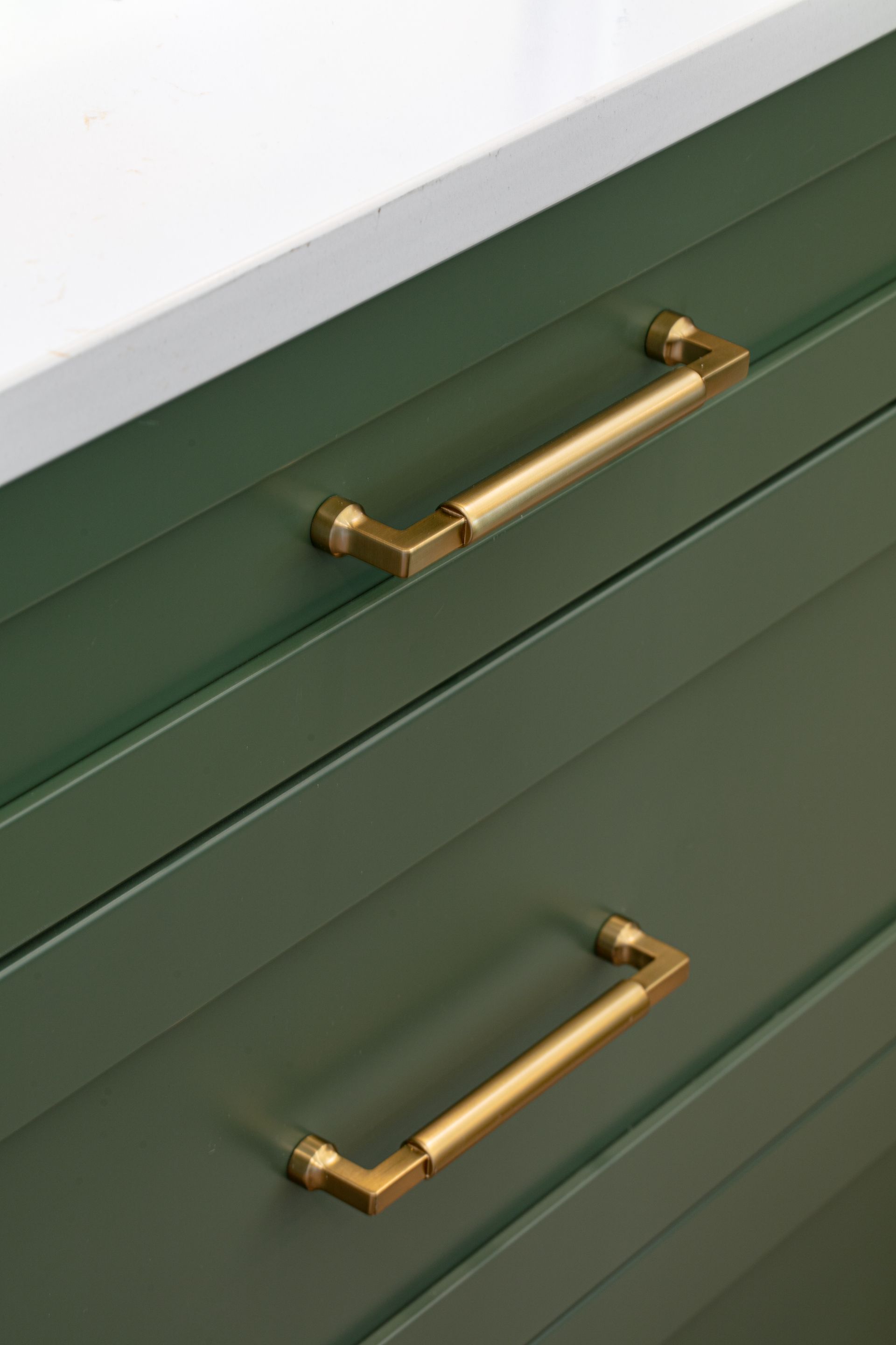 Green cabinet drawers with gold handles.