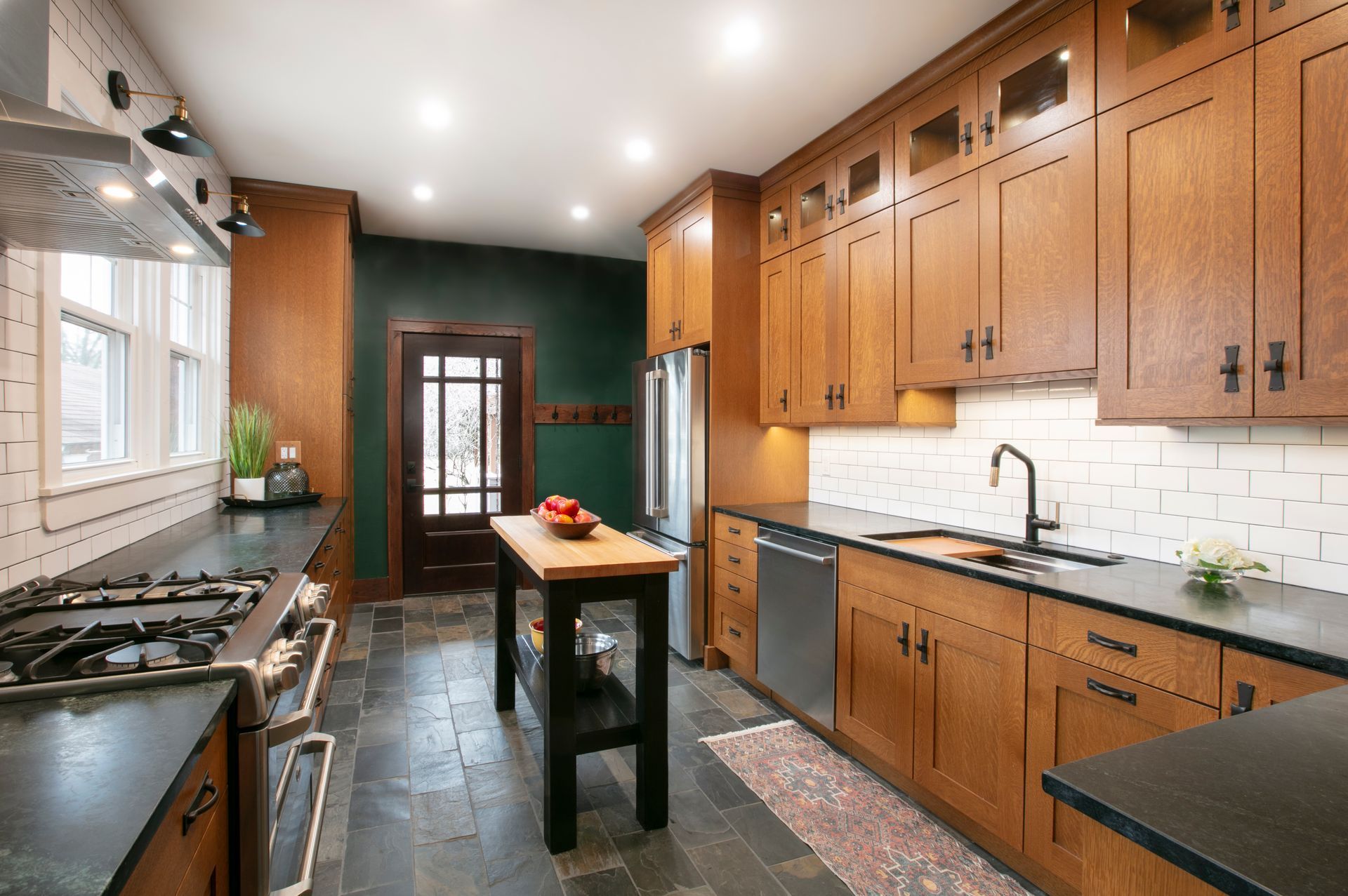 Kitchen with dark wood cabinets, black countertops, and slate flooring.