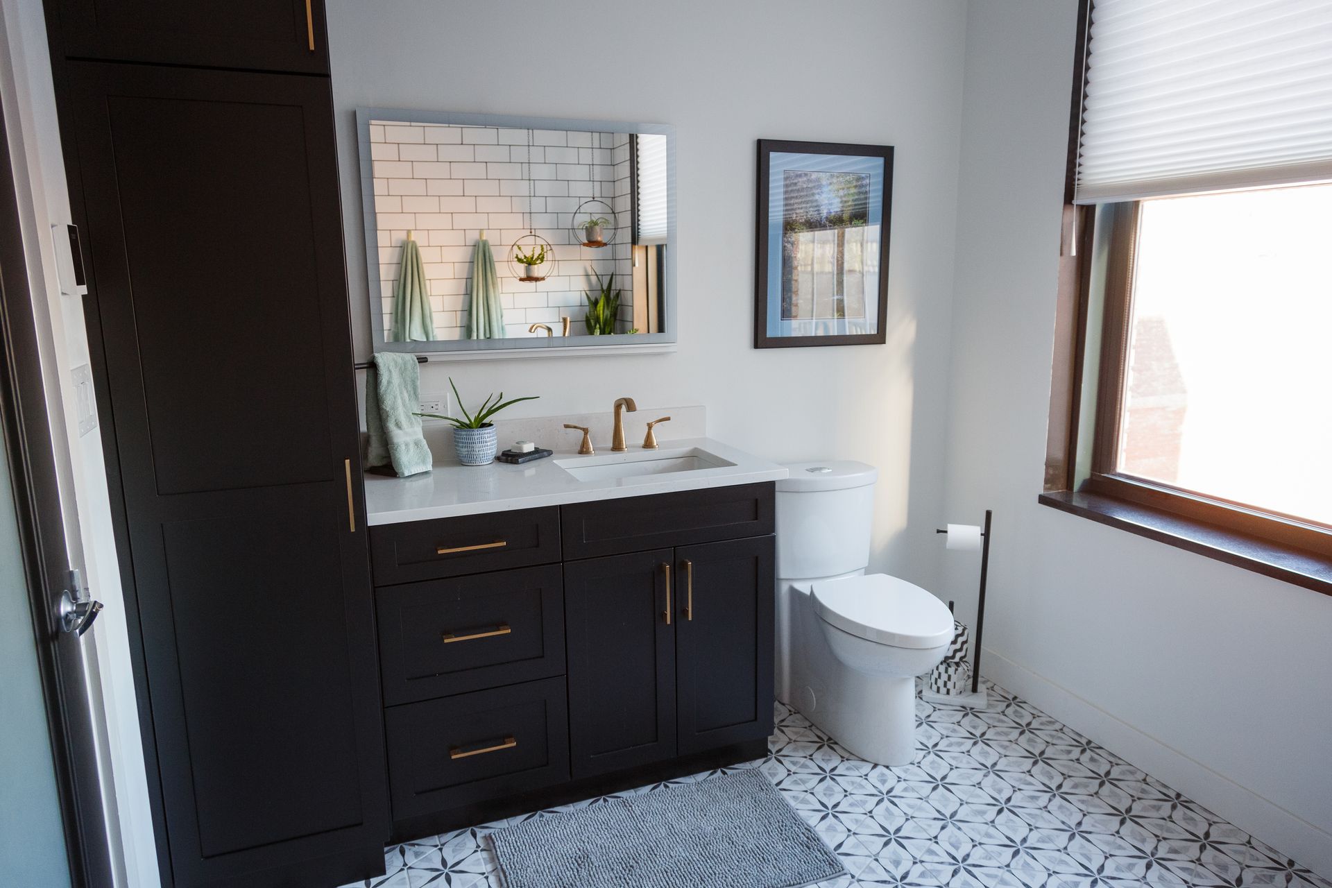 Bathroom with dark cabinets, white tile floor, and a window with blinds.