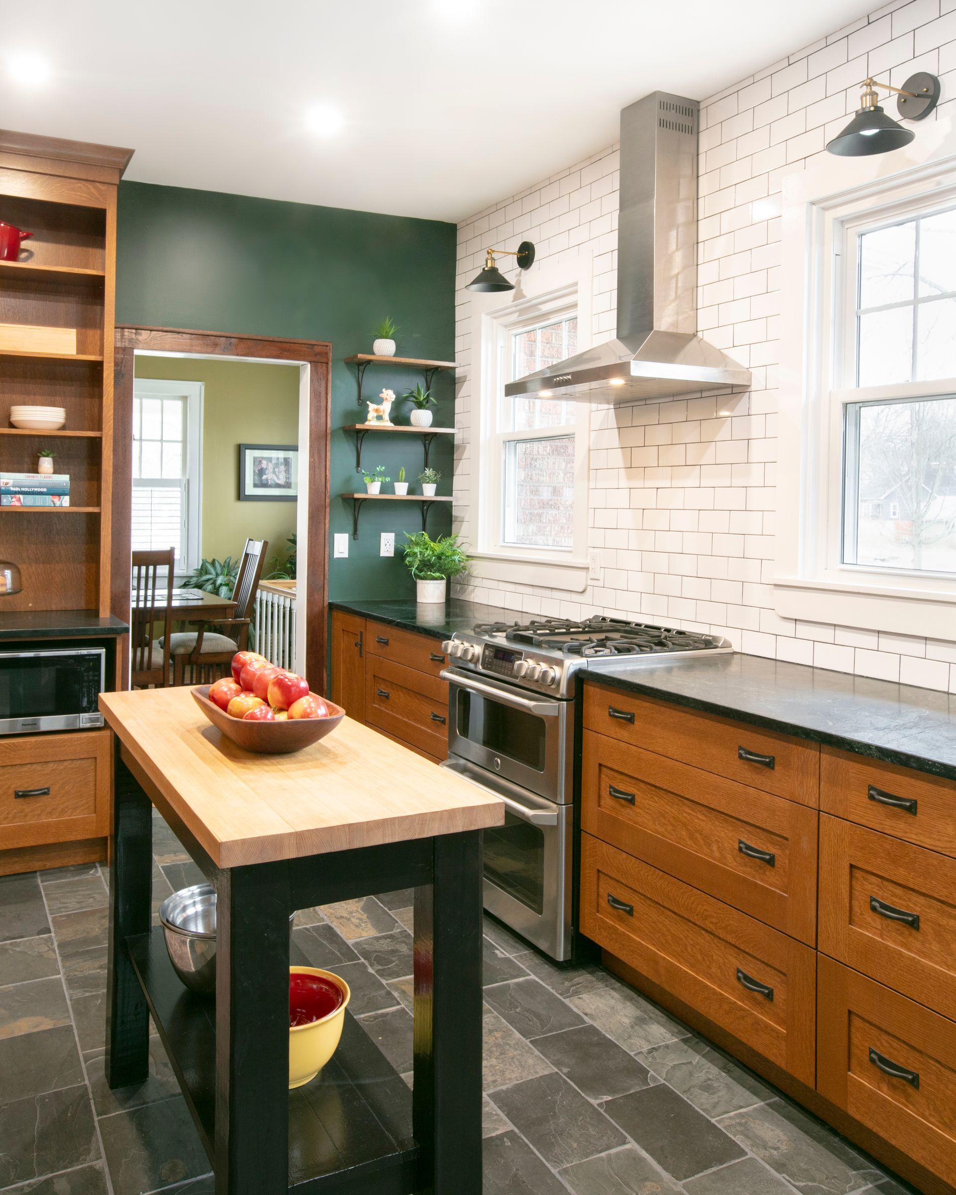 Kitchen with wooden cabinets, a stainless steel range hood, and a dark green accent wall.