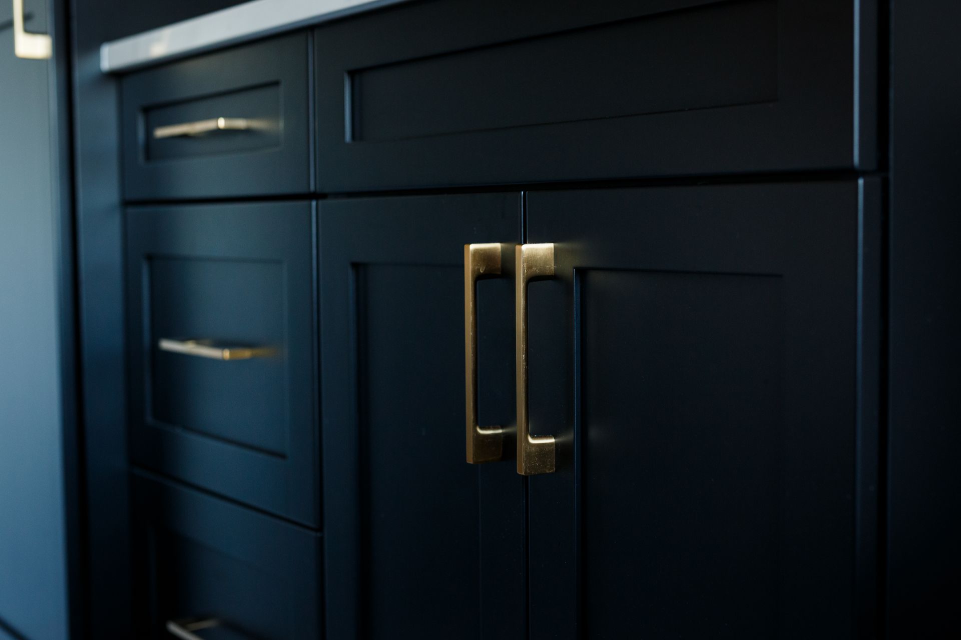 Close-up of black cabinets with gold handles.