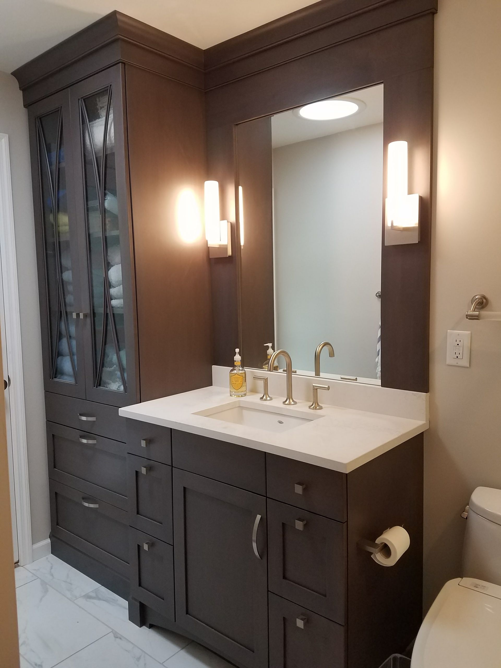 Dark gray bathroom vanity with a storage cabinet, mirror, and two wall sconces.