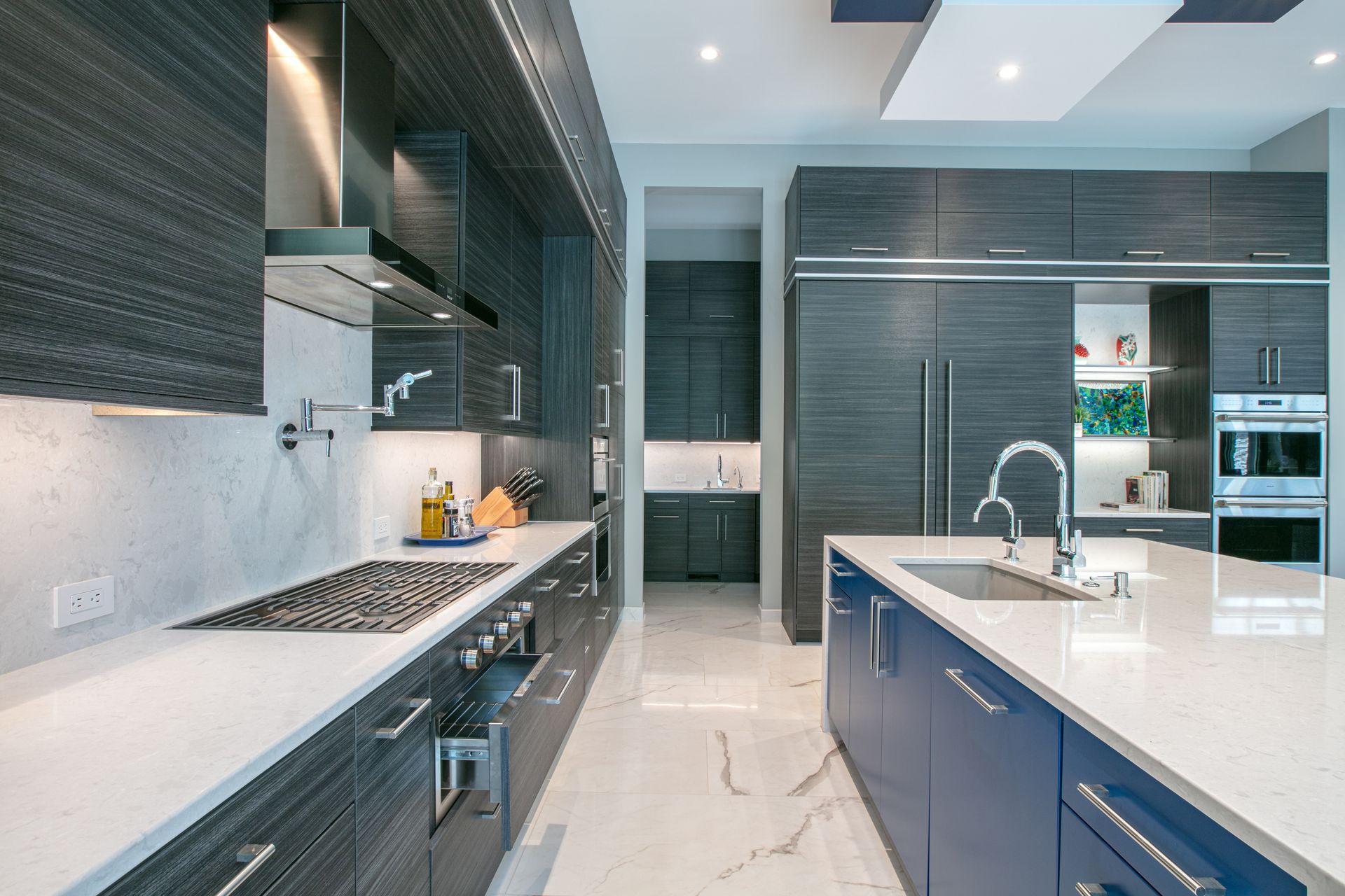 Modern kitchen with dark gray cabinets, white countertops, and blue island.