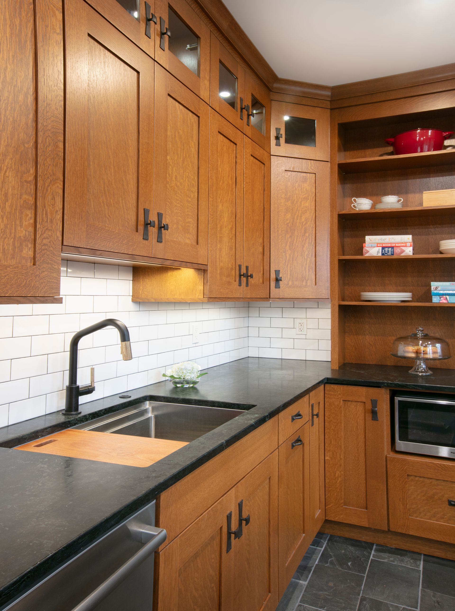 Wooden kitchen cabinets with black countertops and a stainless steel sink.