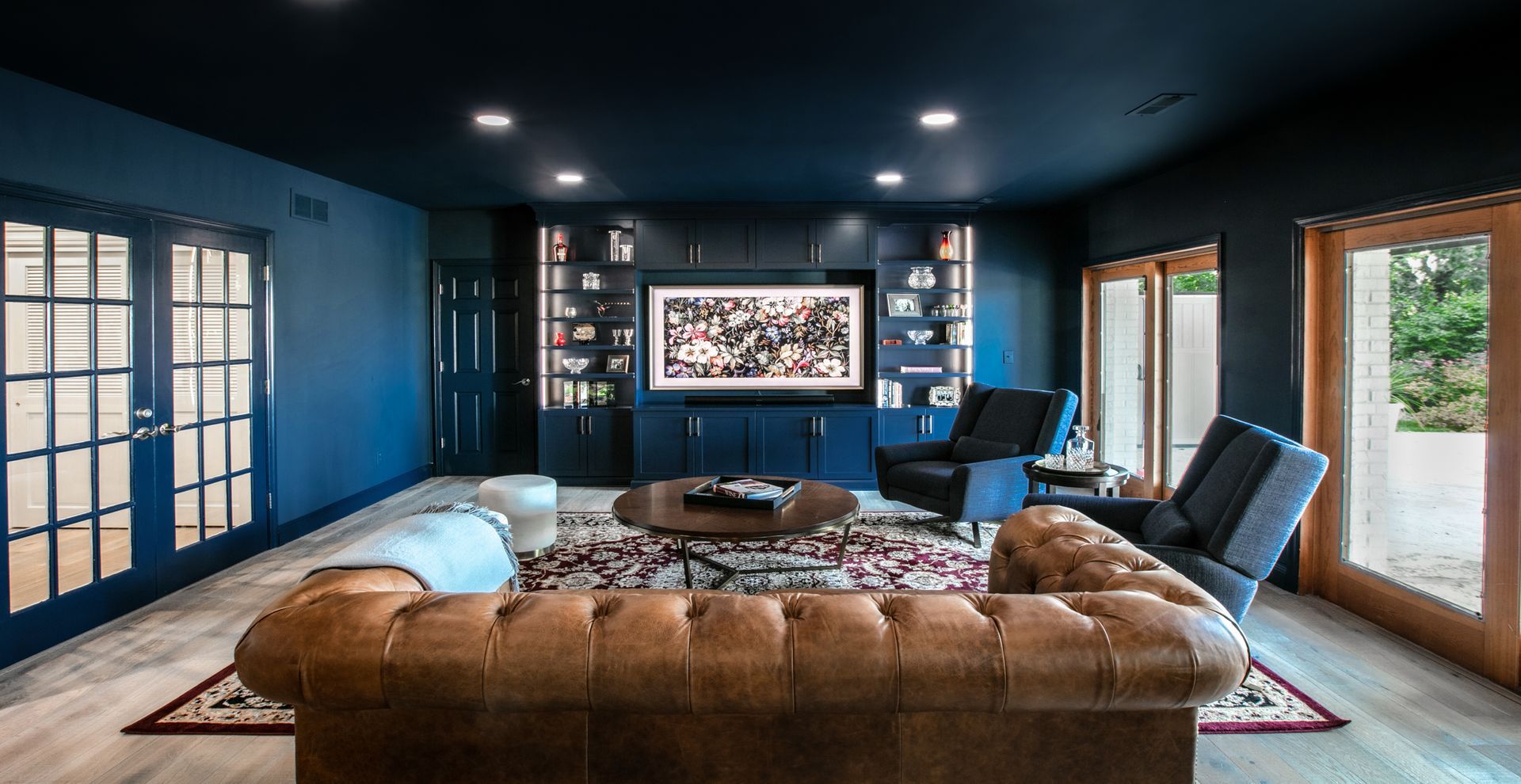 Living room with blue walls, built-in shelves, a brown leather sofa, and a large rug.