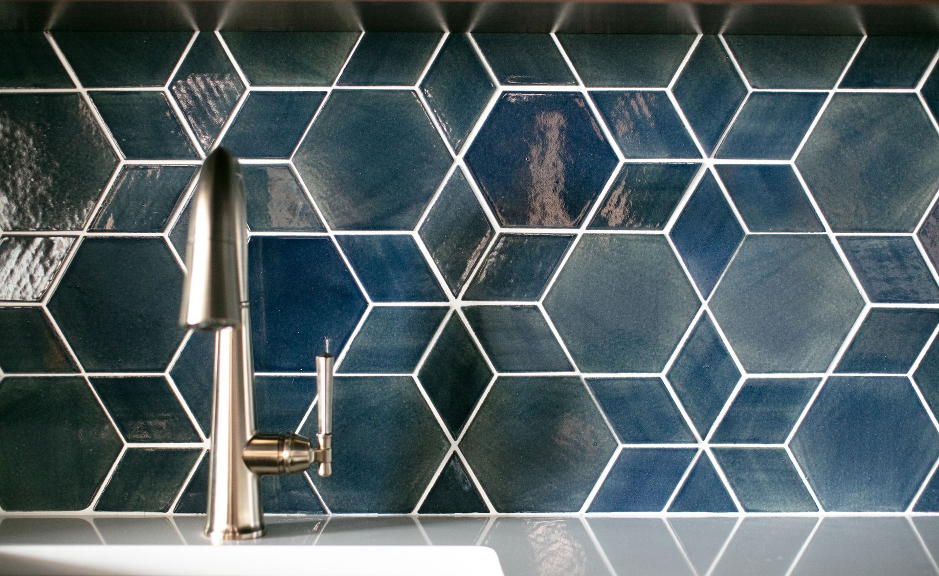 Blue geometric tile backsplash with a silver faucet.