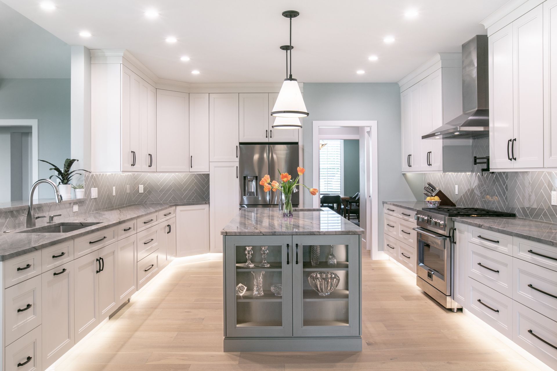 Modern kitchen with white cabinets, gray countertops, island, and stainless steel appliances.