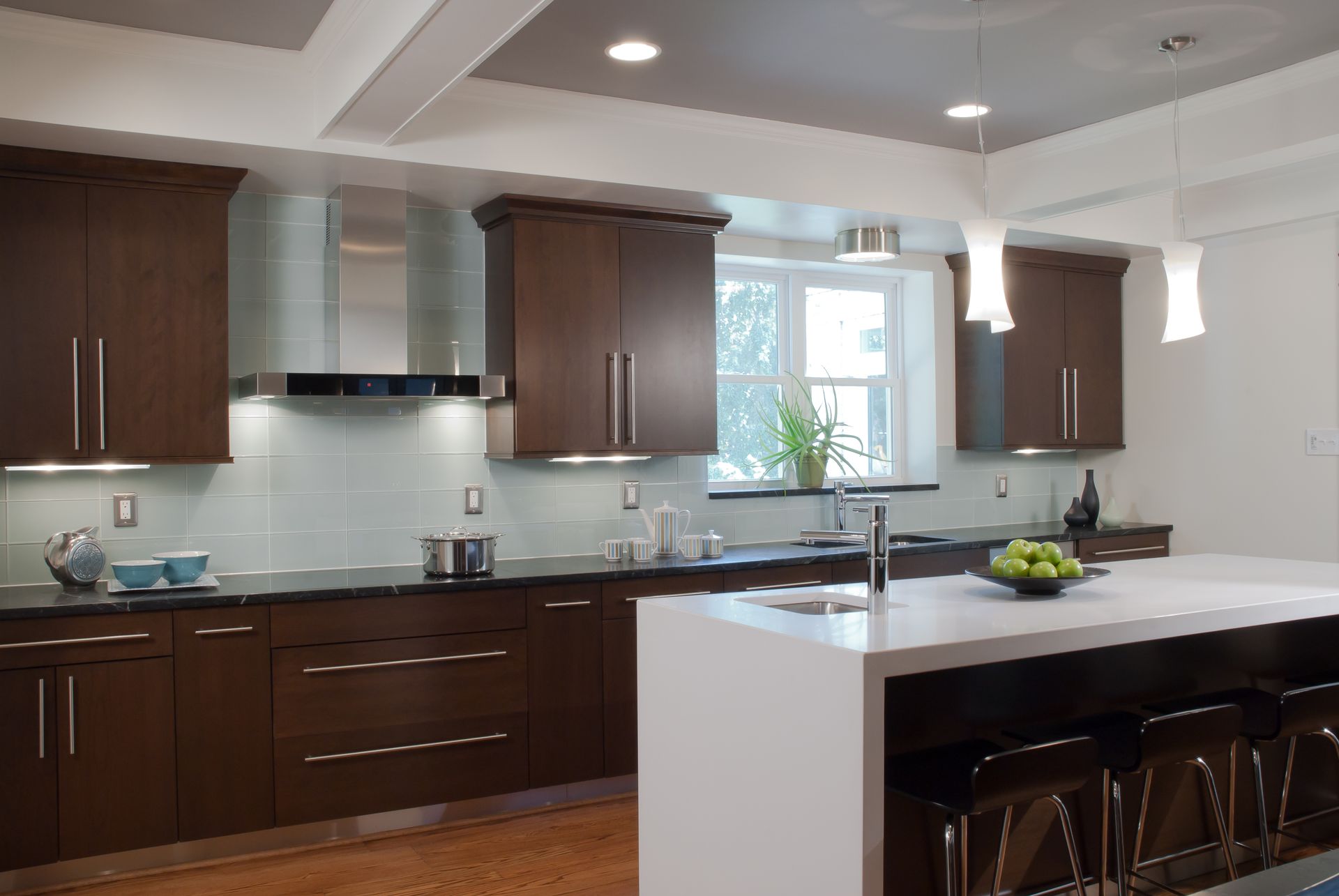 Modern kitchen with dark brown cabinets, light blue backsplash, and white island with seating.