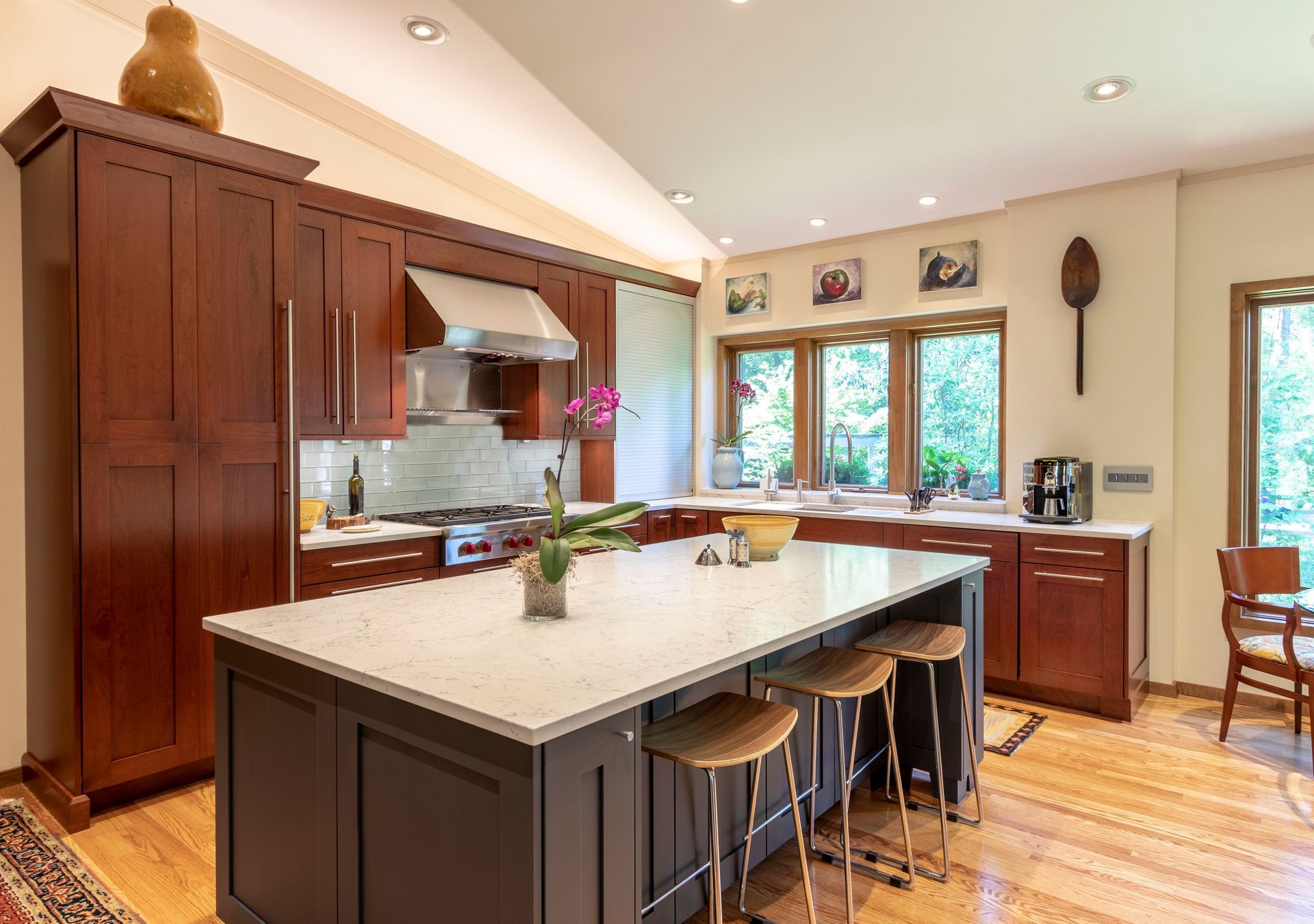 Kitchen with dark wood cabinets, a gray island with a white countertop, and wooden floors.