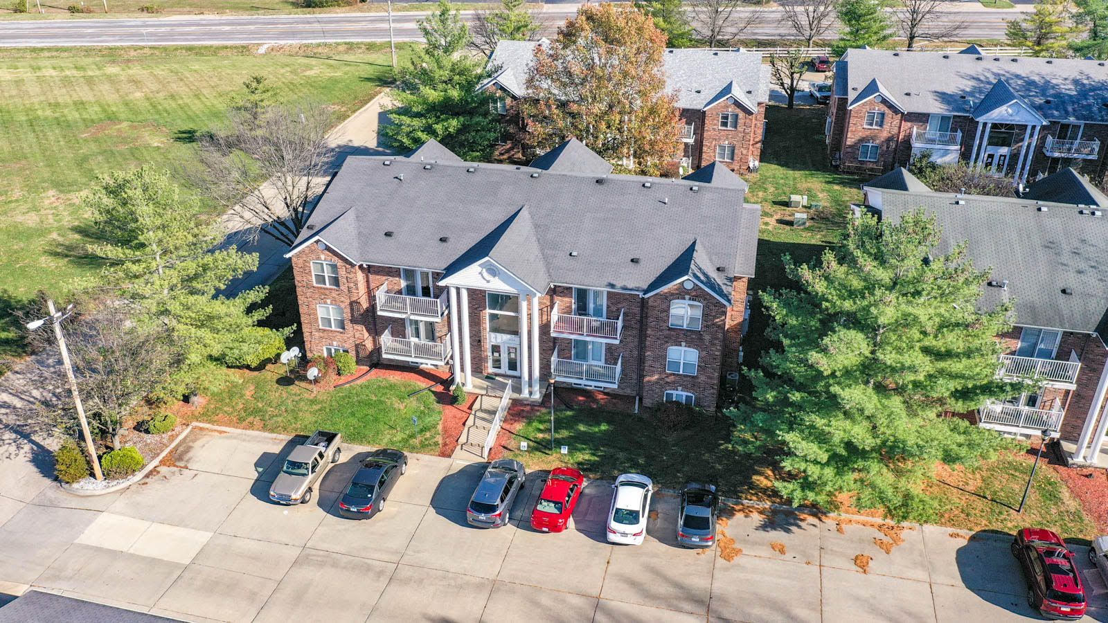 An aerial view of a brick apartment building with cars parked in front of it.