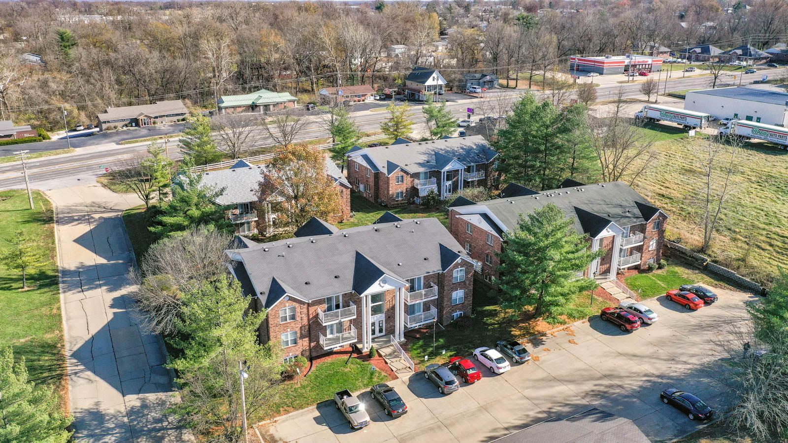 An aerial view of a brick apartment building with cars parked in front of it.