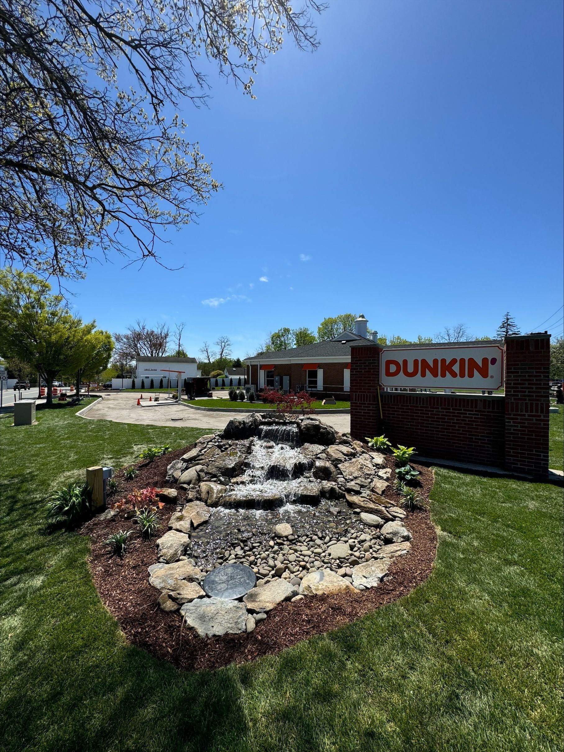 A Dunkin restaurant with a waterfall in front of it.